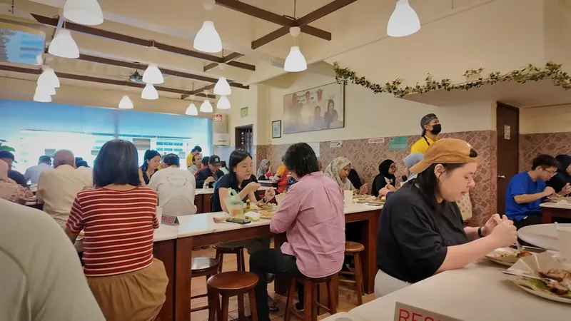 Diners at tables under pendant lamps inside Village Park Restaurant in Damansara Uptown