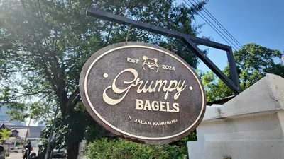 The round wooden Grumpy Bagels sign hanging outside the cafe on Jalan Kamuning, Kuala Lumpur