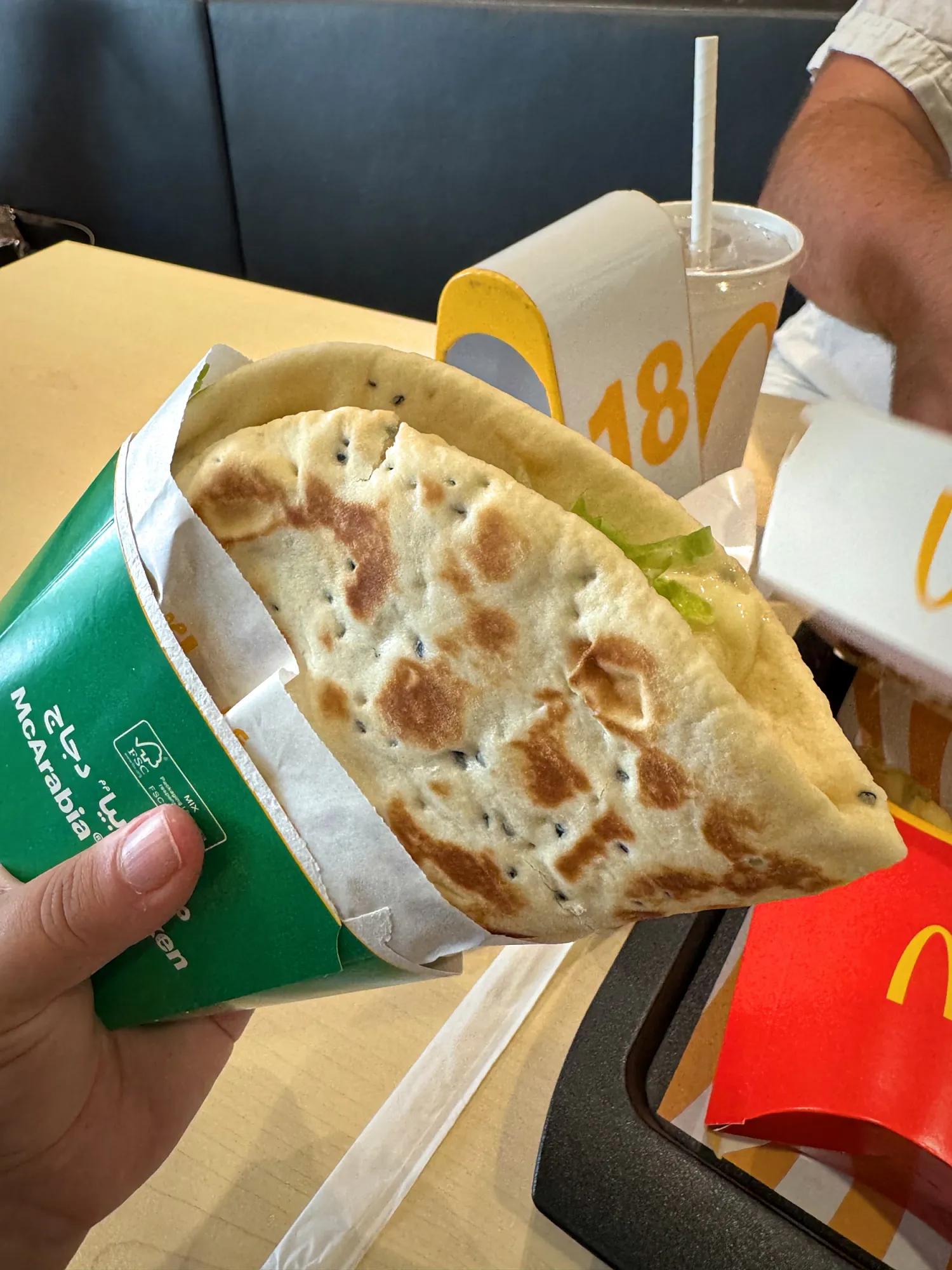 A McArabia chicken flatbread sandwich held up in its green wrapper at McDonald's in Dubai.