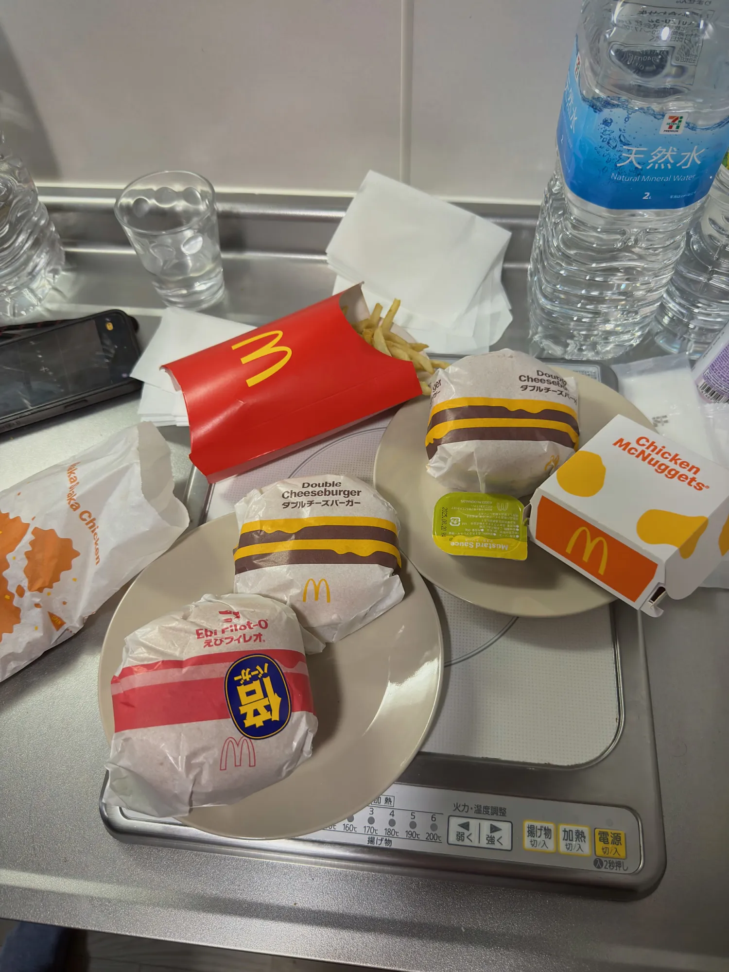 McDonald's takeout in Osaka: an Ebi Filet-O, Double Cheeseburgers, fries, and Chicken McNuggets on an apartment stovetop.