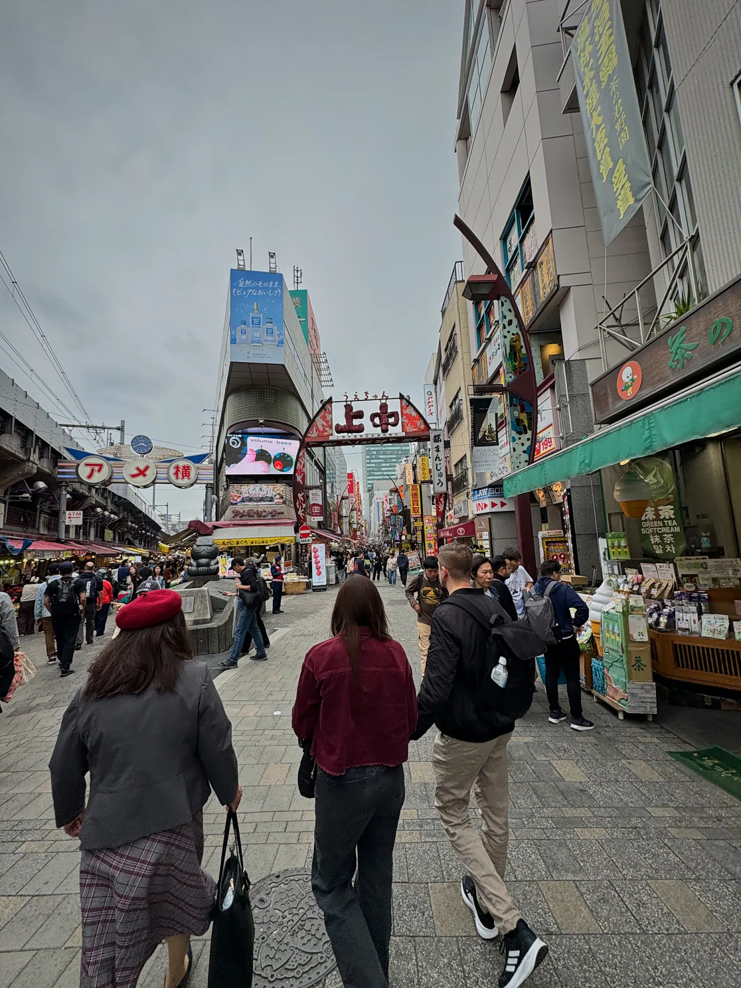 Shoppers walking down Ameyoko market street in Ueno, Tokyo, lined with shops and signs.