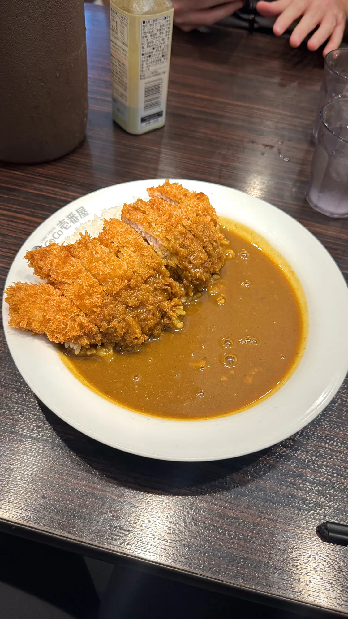A plate of chicken katsu curry with a golden fried cutlet beside a pool of curry sauce in Tokyo