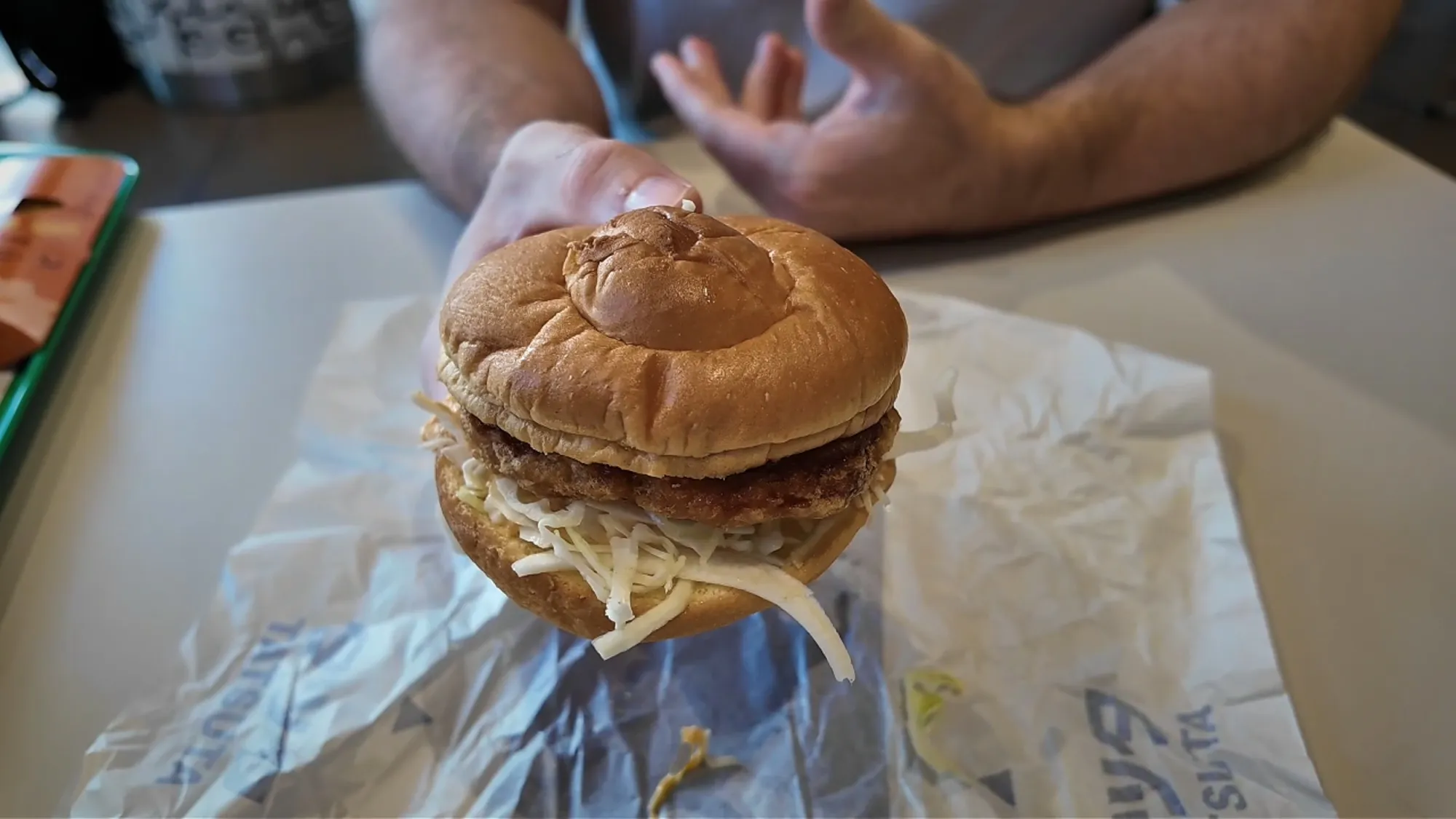 A Chicken Tatsuta burger held up at McDonald's in Japan, with a fried chicken patty and shredded cabbage in a soft bun.