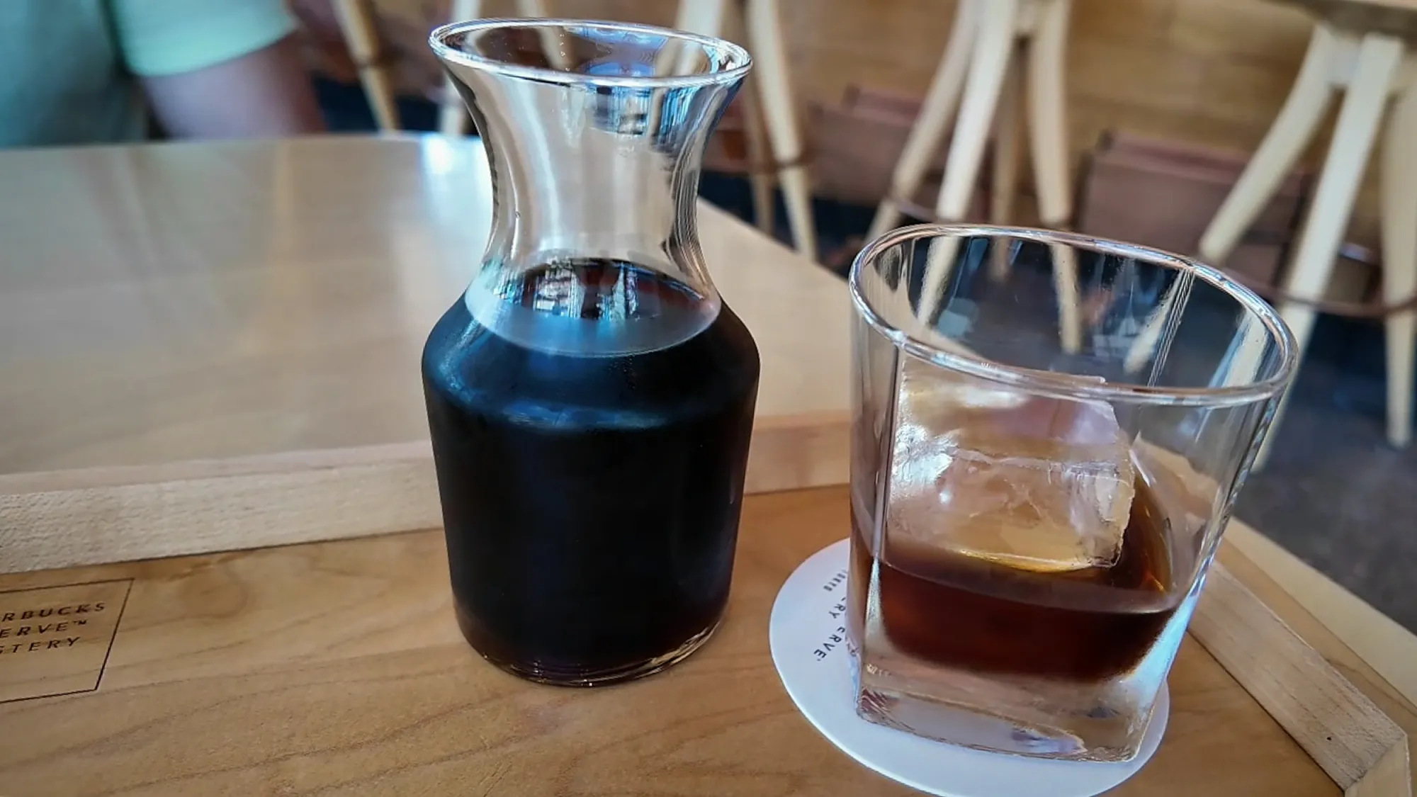 A carafe of barrel-aged cold brew next to a glass of it poured over one big ice cube at Starbucks Reserve Roastery Tokyo.