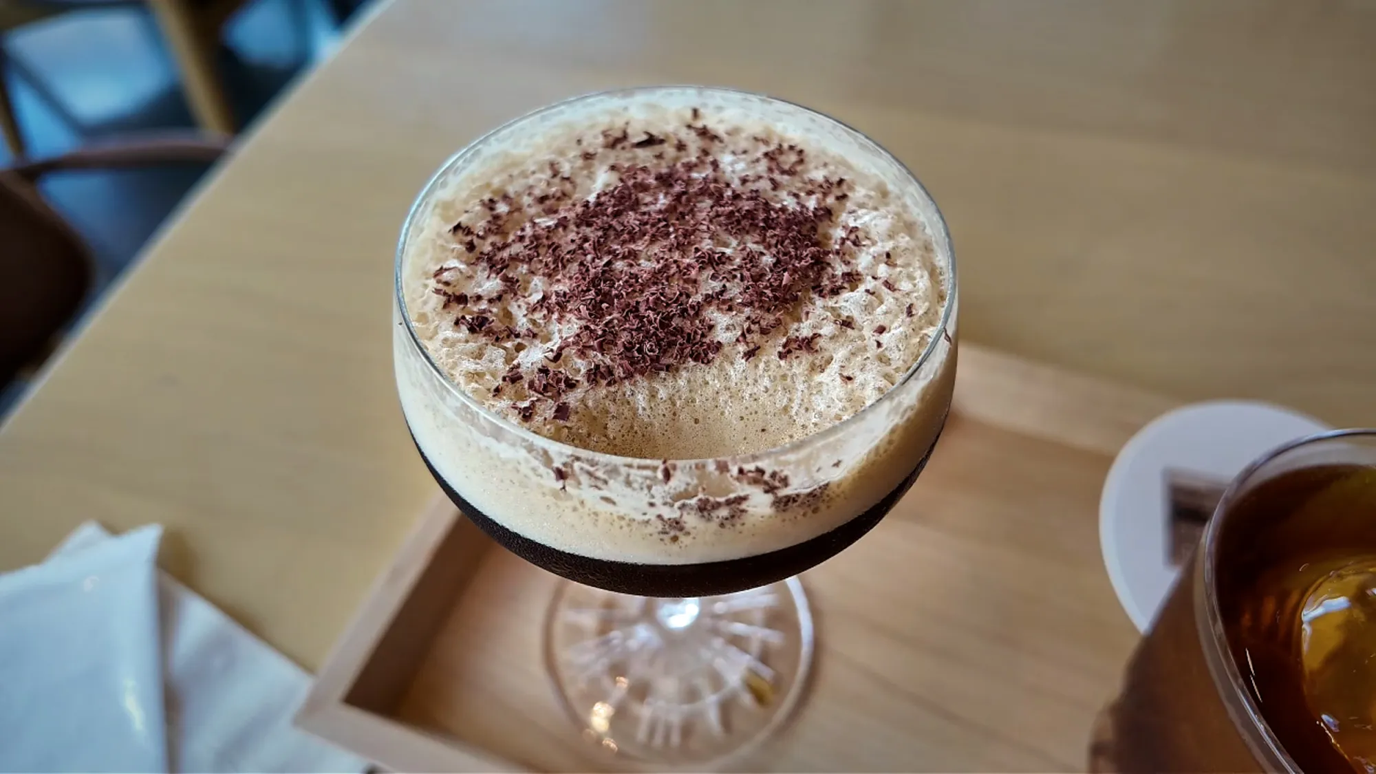 Close-up of a Starbucks Reserve Espresso Martini with thick foam and chocolate shavings in a coupe glass.
