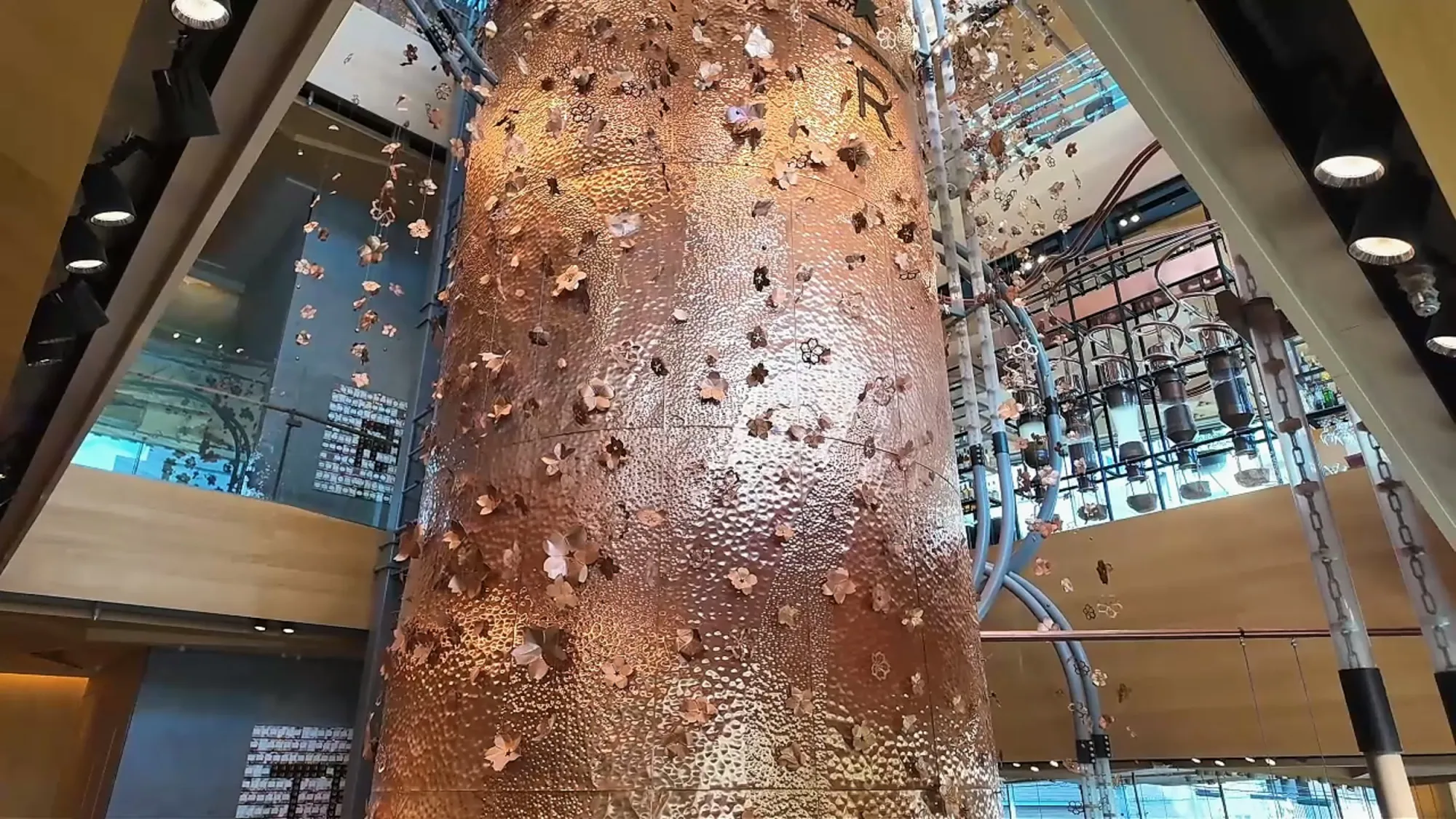 The giant copper cask covered in hammered copper flowers rising through the floors of Starbucks Reserve Roastery Tokyo in Nakameguro.