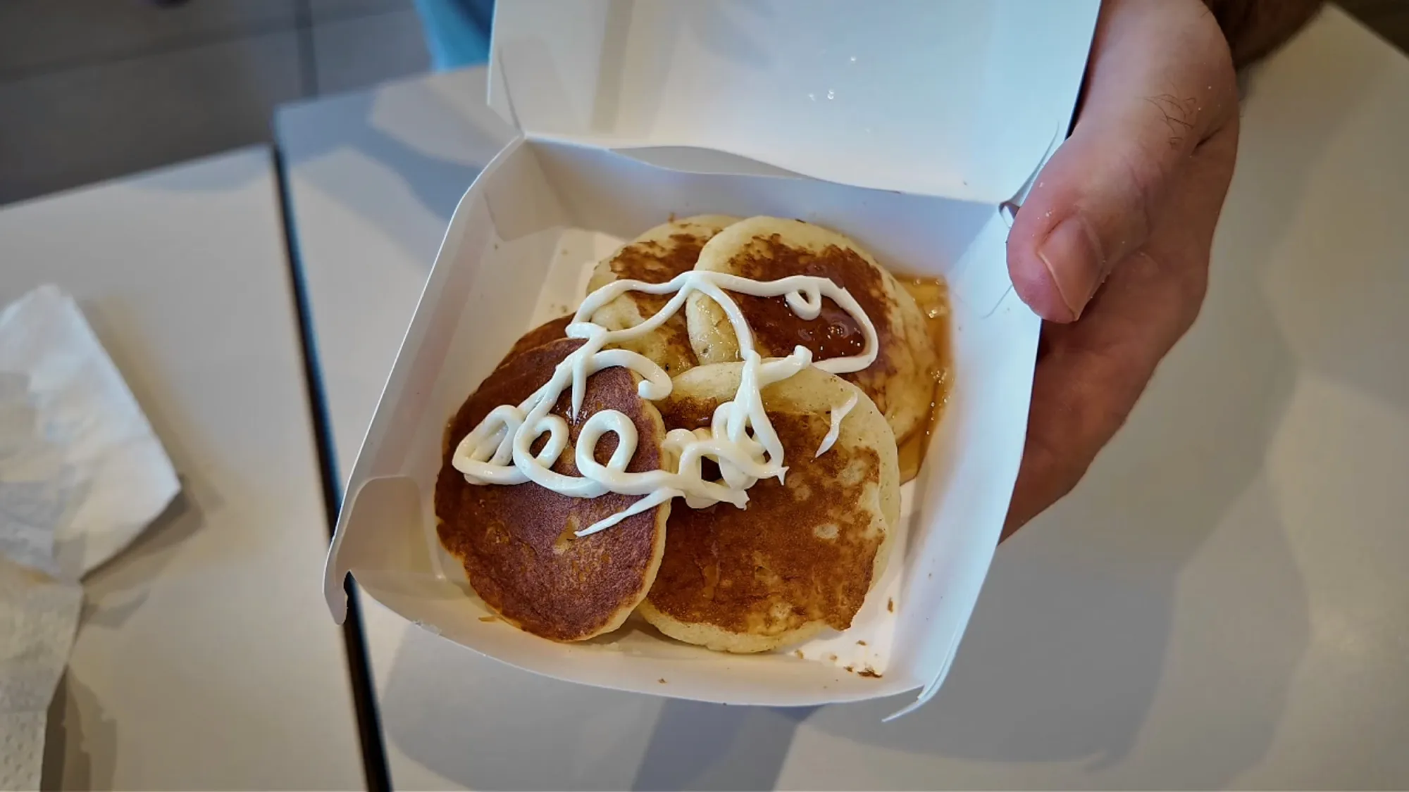 Petite Pancakes in an open box at McDonald's in Japan, with the apple and cream topping squeezed over them.