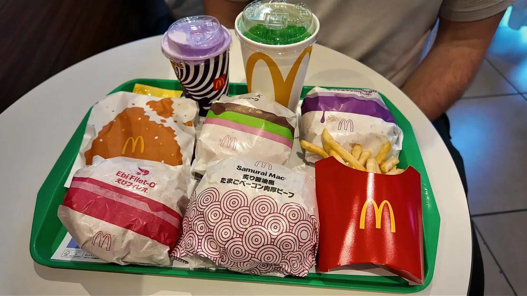 A McDonald's Japan lunch tray with the Samurai Mac, Ebi Filet-O, Teriyaki McBurger, McPork, a Shaka Shaka Chicken bag, fries, a purple Grimace Shake, and a green Fanta Melon.