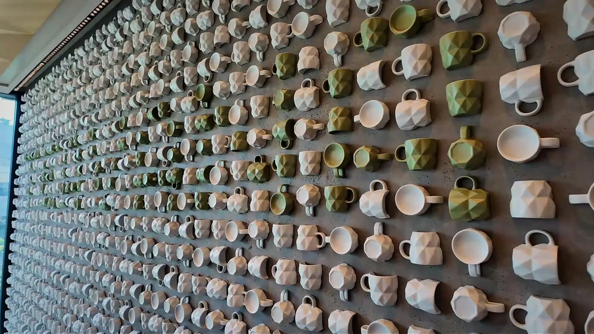 A wall of white and green ceramic teacups set at different angles on the Teavana floor of Starbucks Reserve Roastery Tokyo.