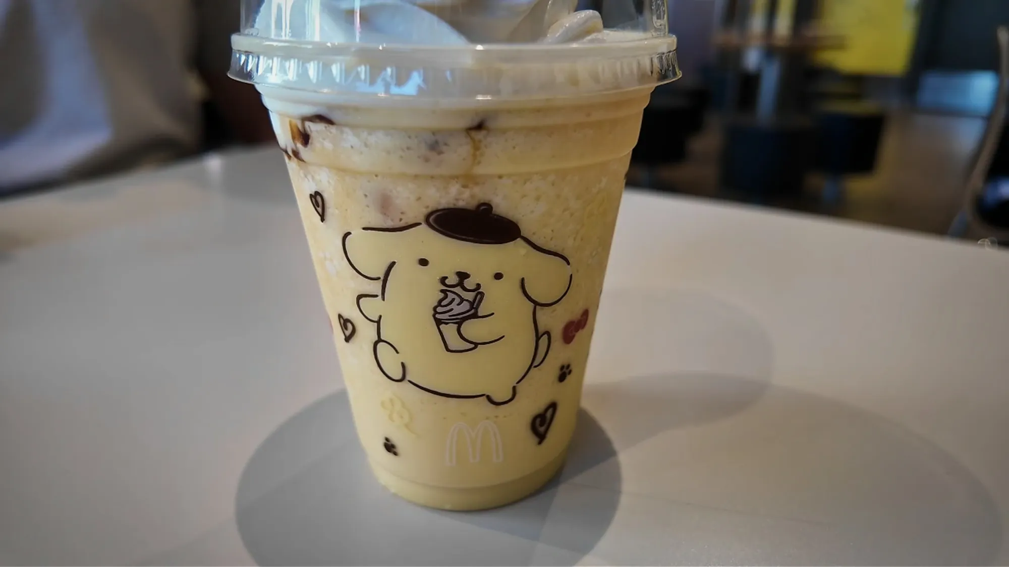 A Pompompurin Frappé at McDonald's in Japan, a creamy drink in a clear cup printed with the Sanrio dog Pompompurin.