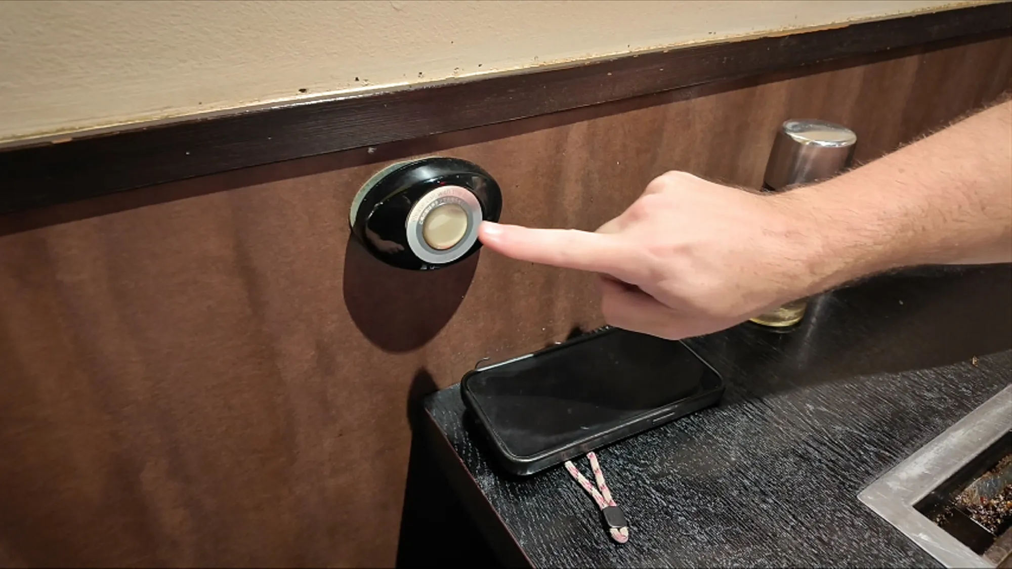 A finger pressing the call button on the edge of a restaurant table in Tokyo.