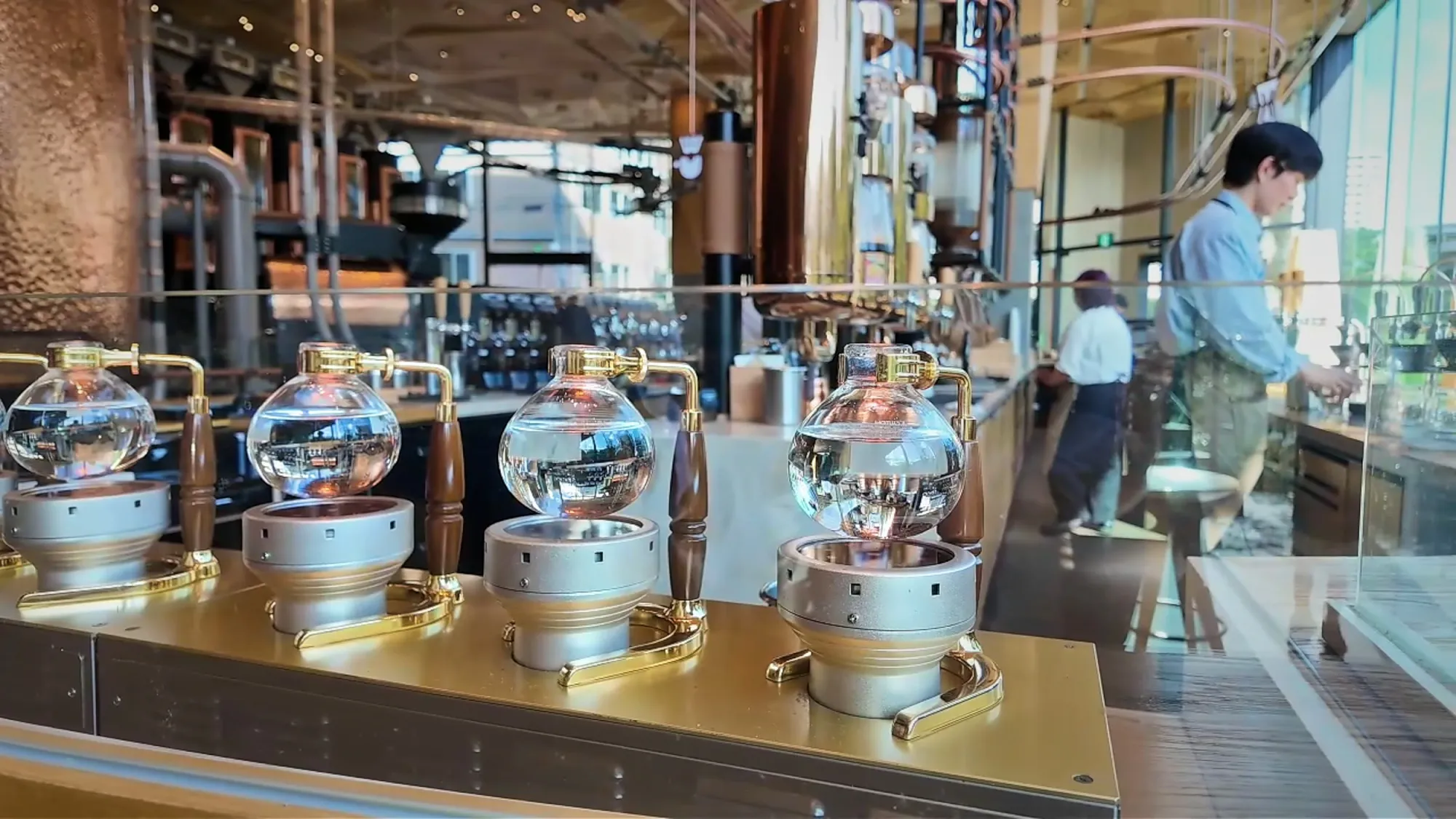 A row of glass siphon coffee brewers on the coffee bar at Starbucks Reserve Roastery Tokyo.