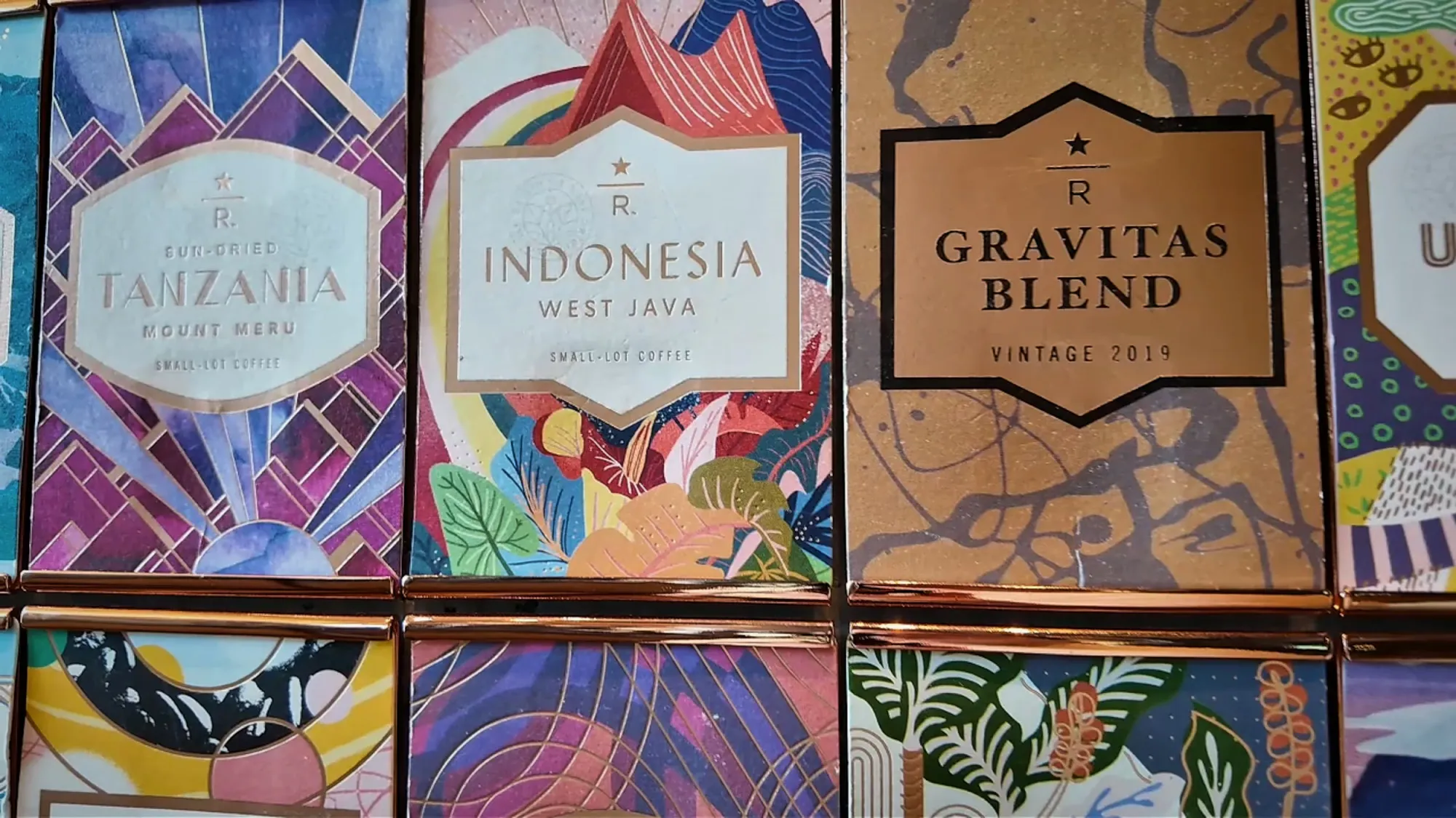 Colorful Starbucks Reserve coffee bean bags, including Gravitas Blend and Indonesia, on display at Starbucks Reserve Roastery Tokyo.