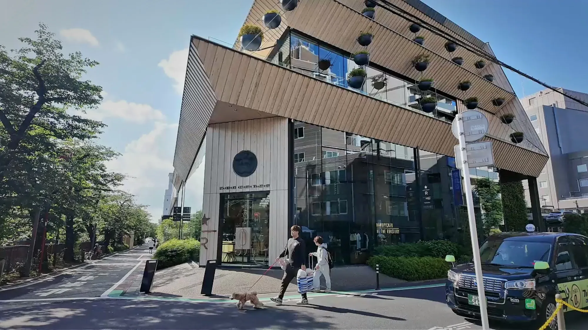The wood-slatted Starbucks Reserve Roastery building beside the tree-lined Meguro River walk in Nakameguro, Tokyo.