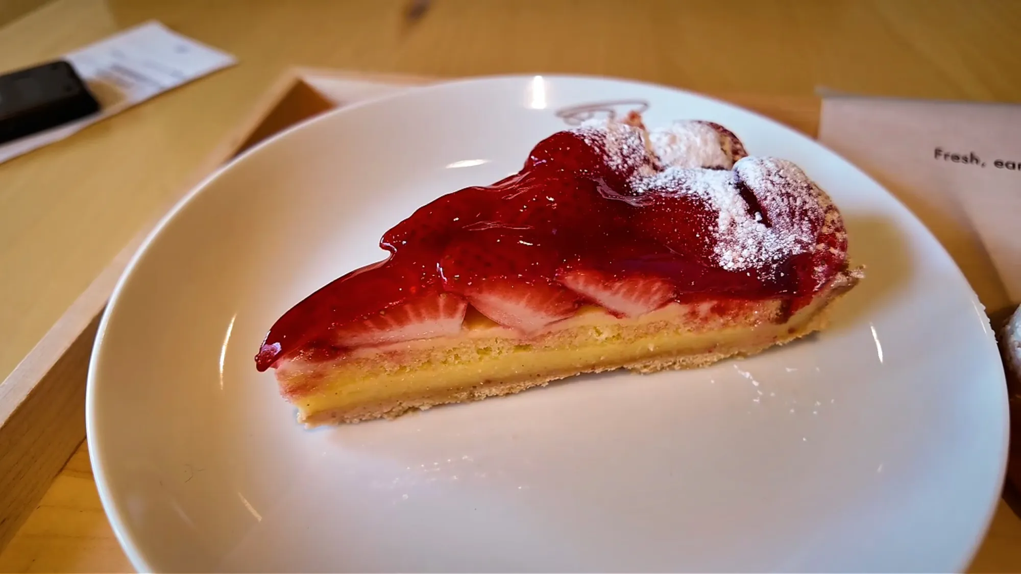 A slice of strawberry tart dusted with powdered sugar on a white plate at Starbucks Reserve Roastery Tokyo.