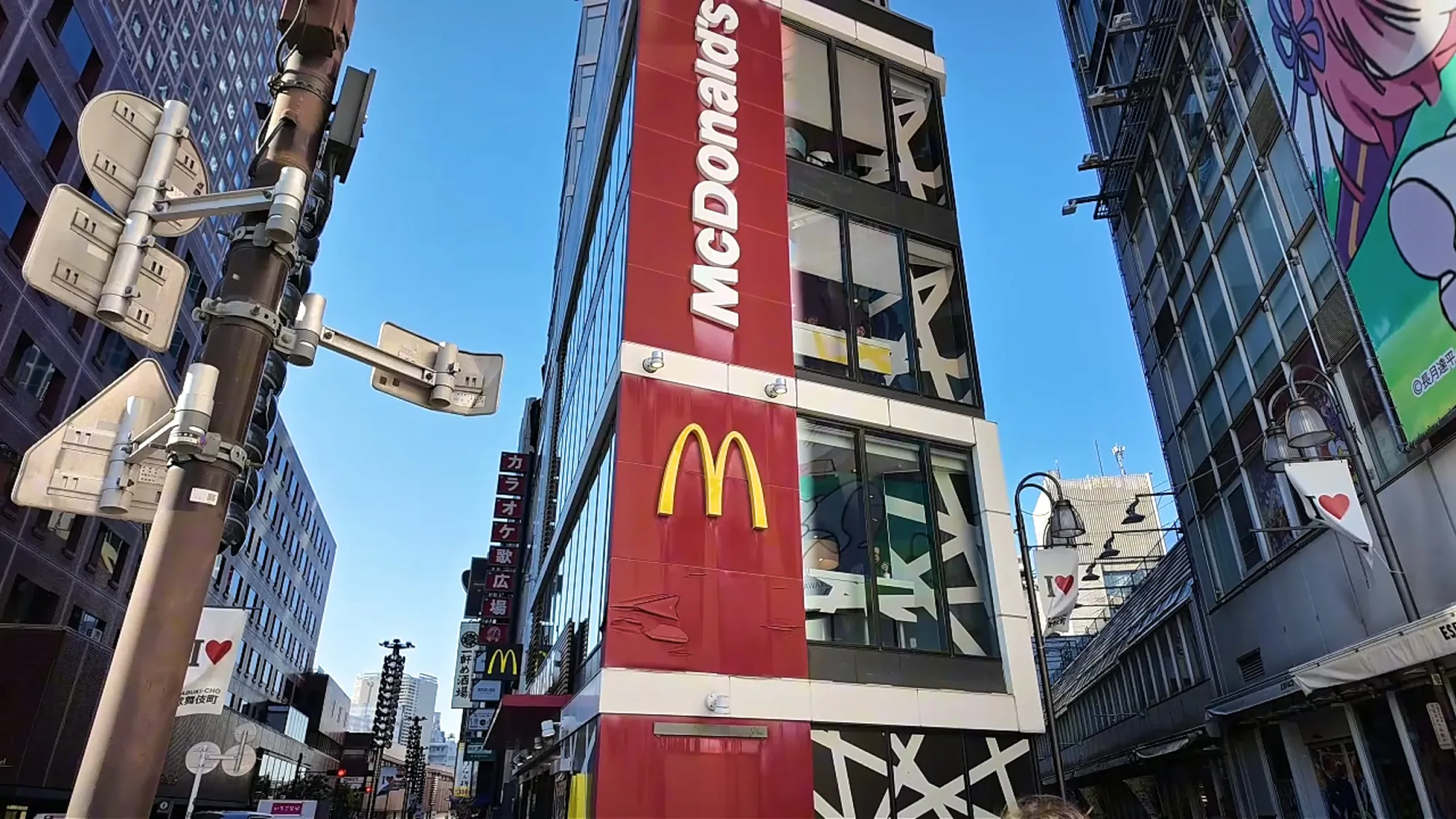 The tall red McDonald's building on a street in Shinjuku, Tokyo, with the golden arches on the front.