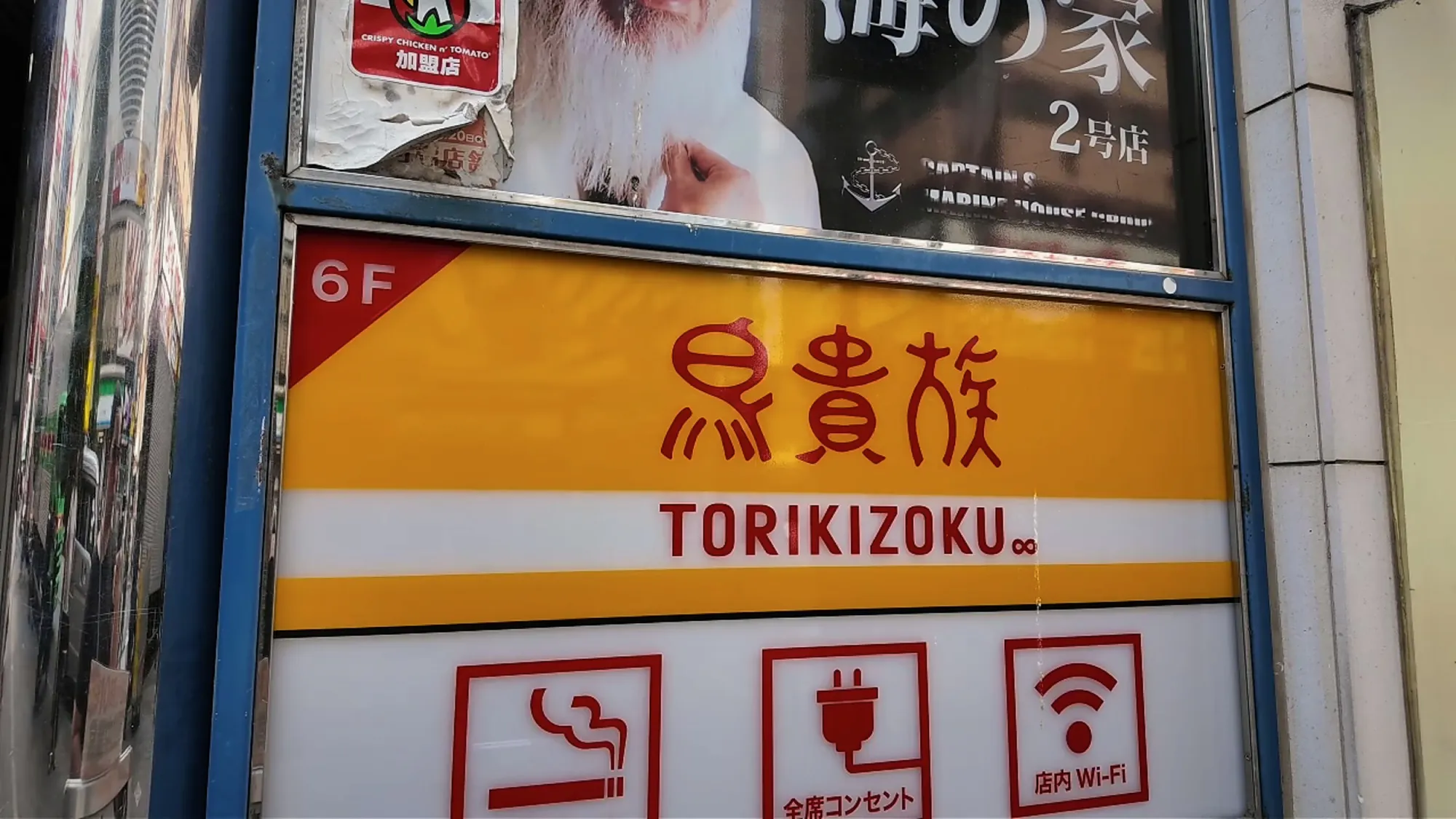 The yellow and red Torikizoku sign for the sixth-floor restaurant on a building directory on Central Road in Kabukicho, Shinjuku, Tokyo.
