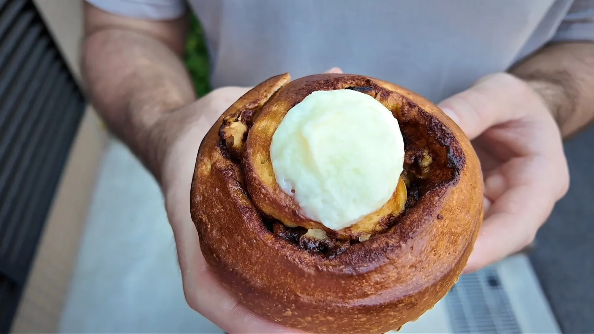 A golden-brown walnut cinnamon roll from Donsuke Bakery topped with a scoop of white icing