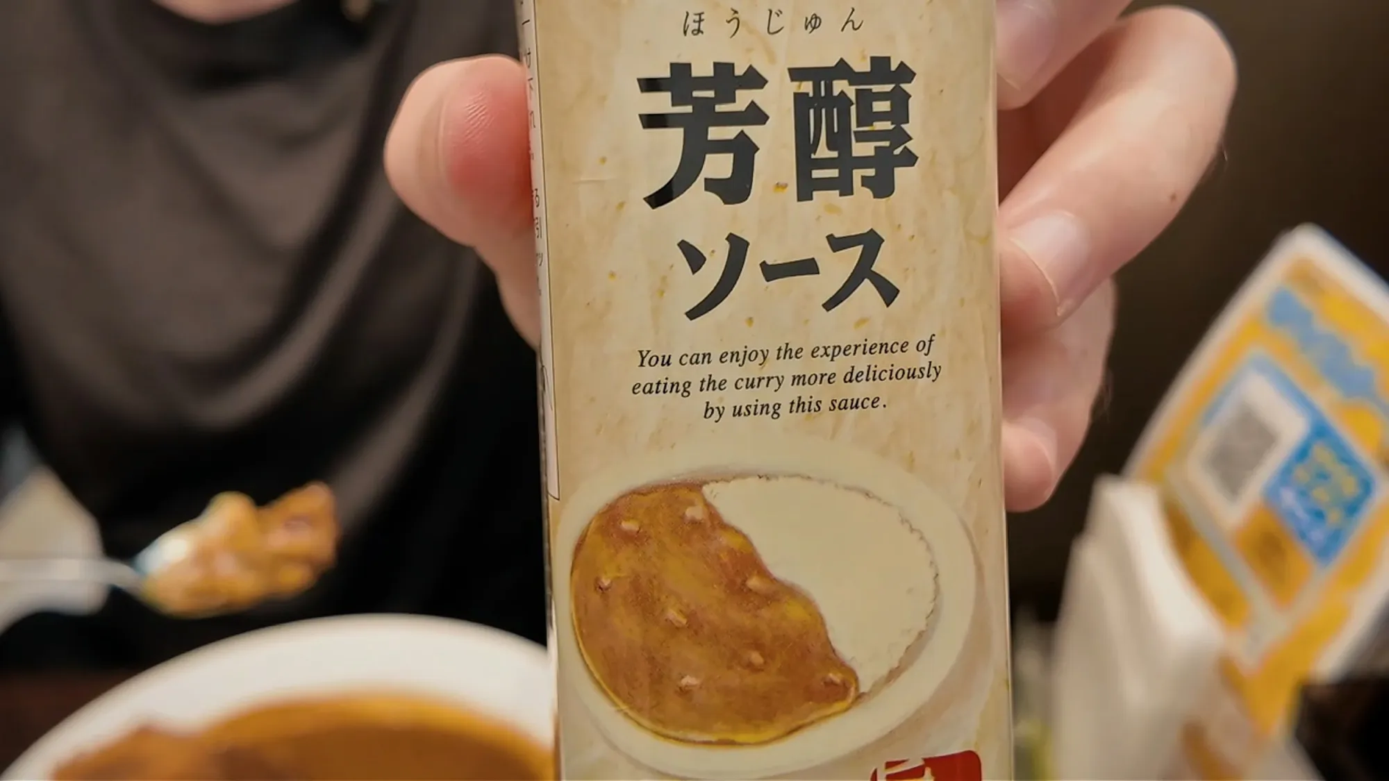 Holding up the bottle of Hojun sauce, a sweet-and-sour curry sauce, at CoCo Ichibanya in Tokyo.