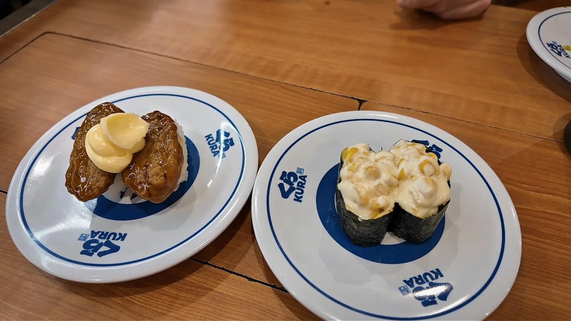 Hamburg steak sushi with mayonnaise and a corn mayo gunkan on Kura Sushi plates.