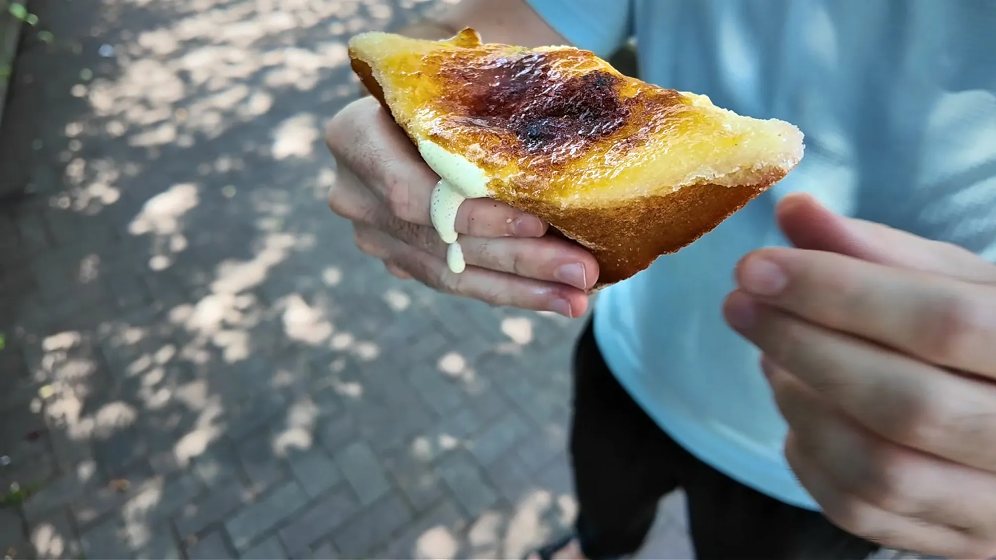 An Age.3 crème brûlée fried sandwich with a caramelized sugar top and custard dripping out of the side.