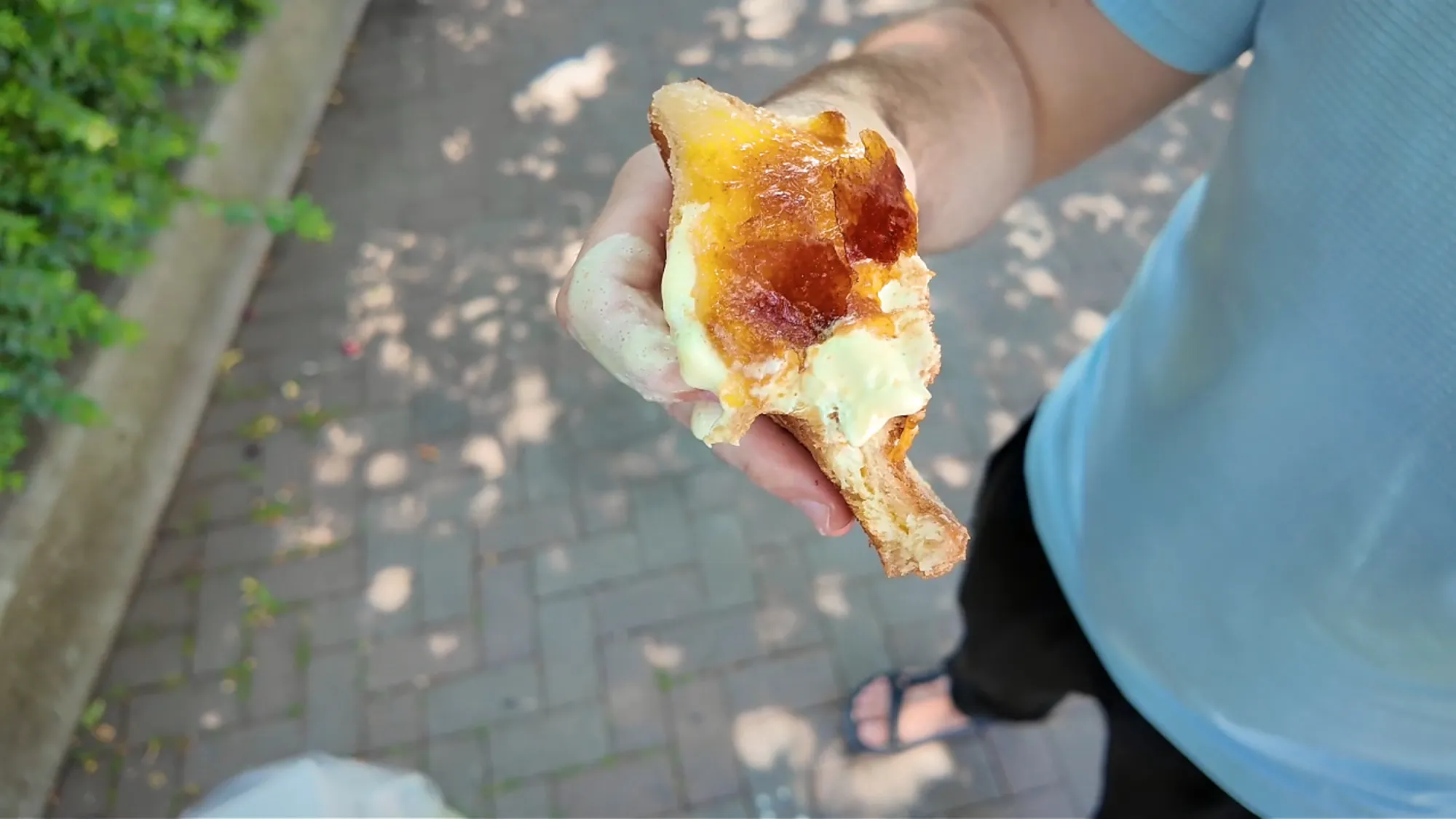 A bitten Age.3 crème brûlée fried sandwich showing the custard filling under the caramelized sugar.