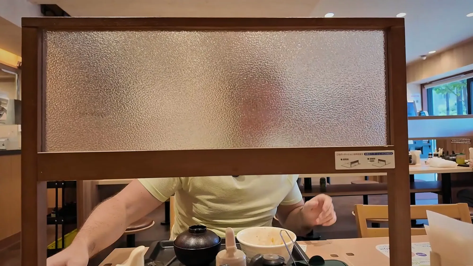 Cream eating behind a frosted privacy divider at a Matsuya table in Tokyo.