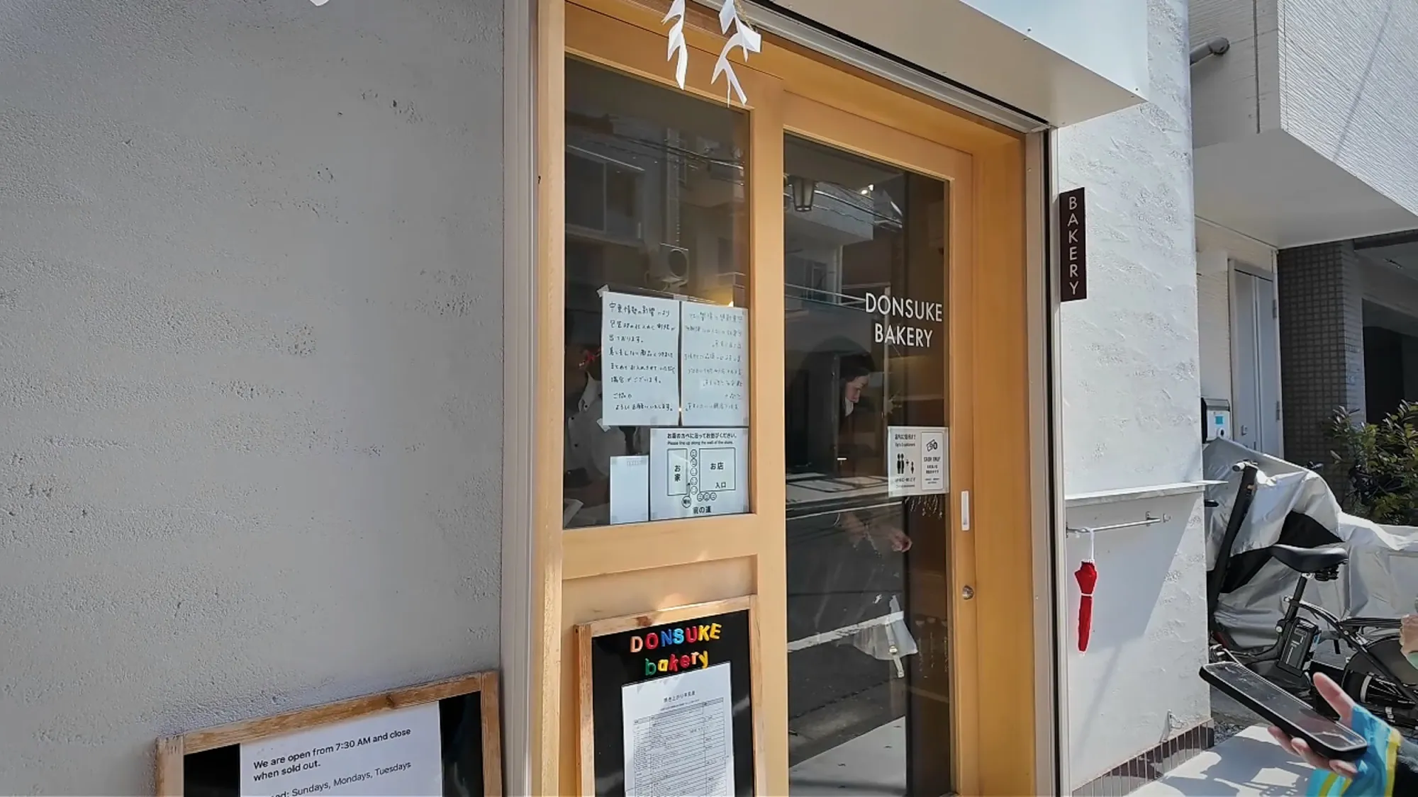 The glass door and small sign of Donsuke Bakery in Shinjuku 7-chome