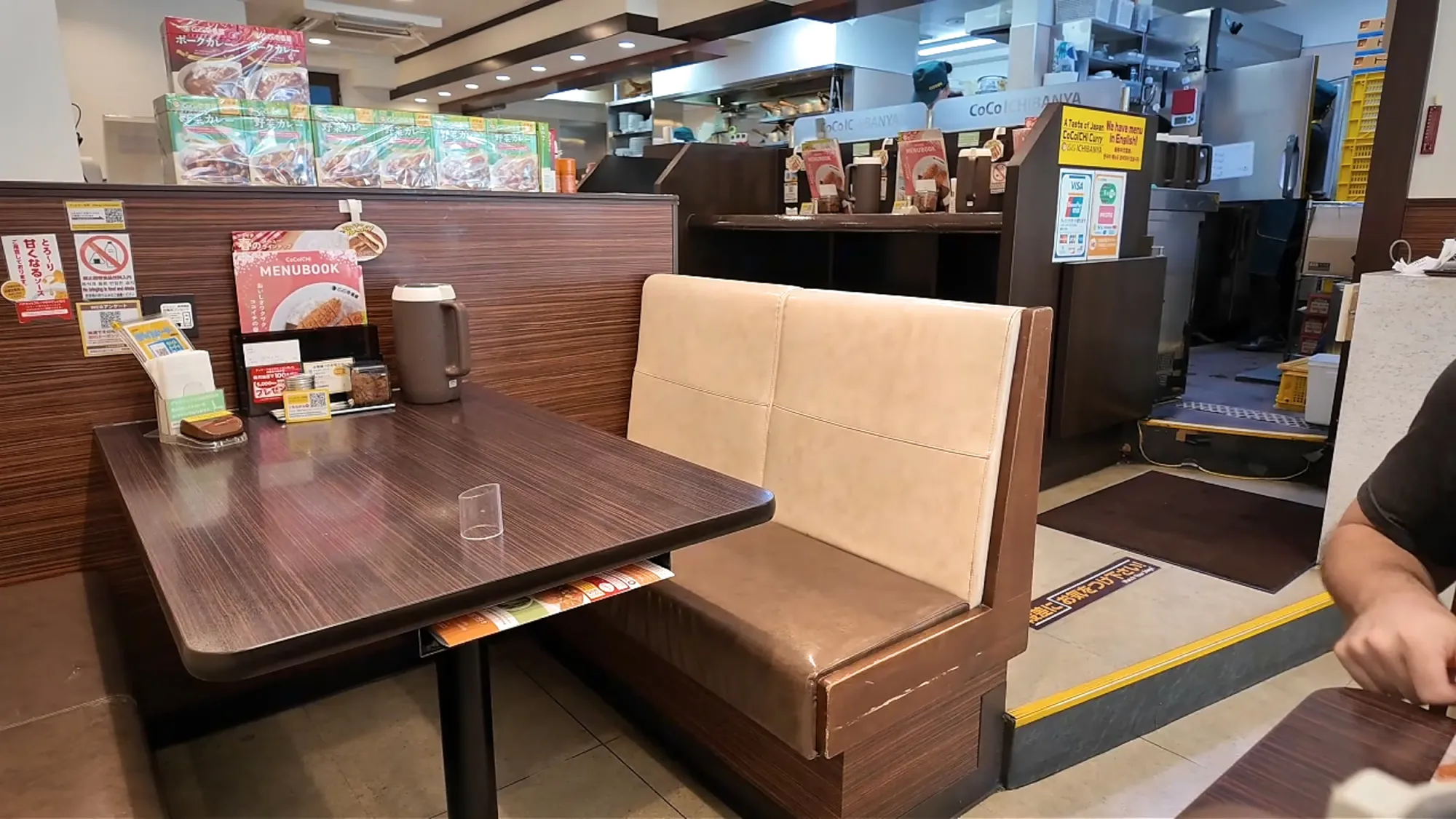 An empty booth with beige seats and a dark wooden table inside CoCo Ichibanya in Tokyo.