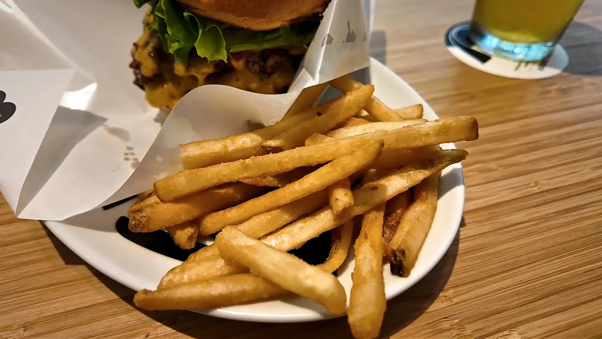 A plate of skin-on fries next to a double cheeseburger in a paper wrap at Shogun Burger in Tokyo.