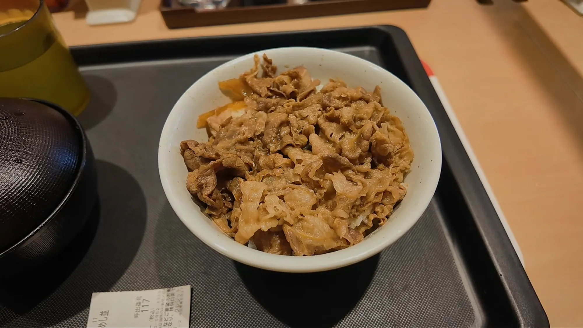 A plain bowl of gyudon, thinly sliced beef and onions over rice, on a tray at Matsuya in Tokyo