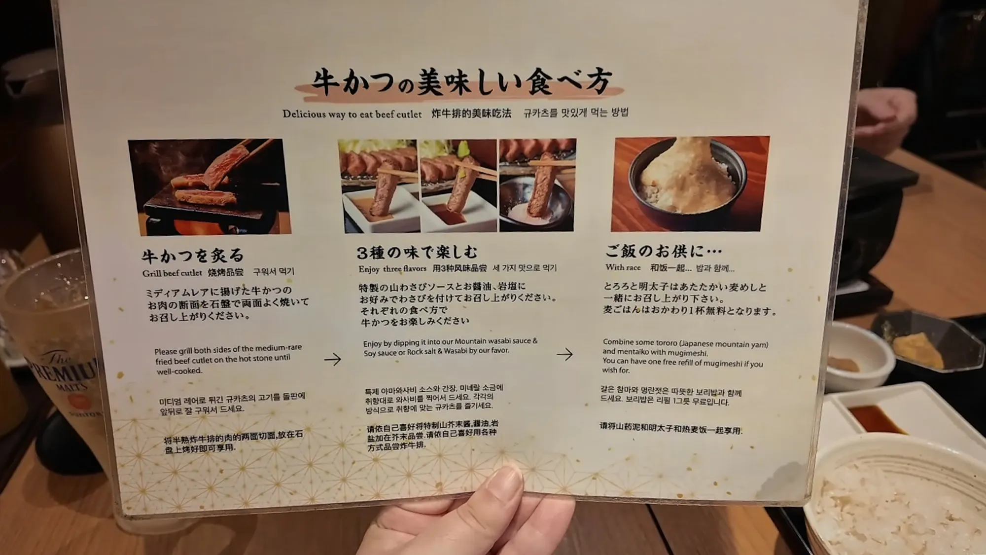 The Gyukatsu Motomura card explaining in English how to eat beef cutlet: grill it on the hot stone, try three flavors, and eat it with rice.