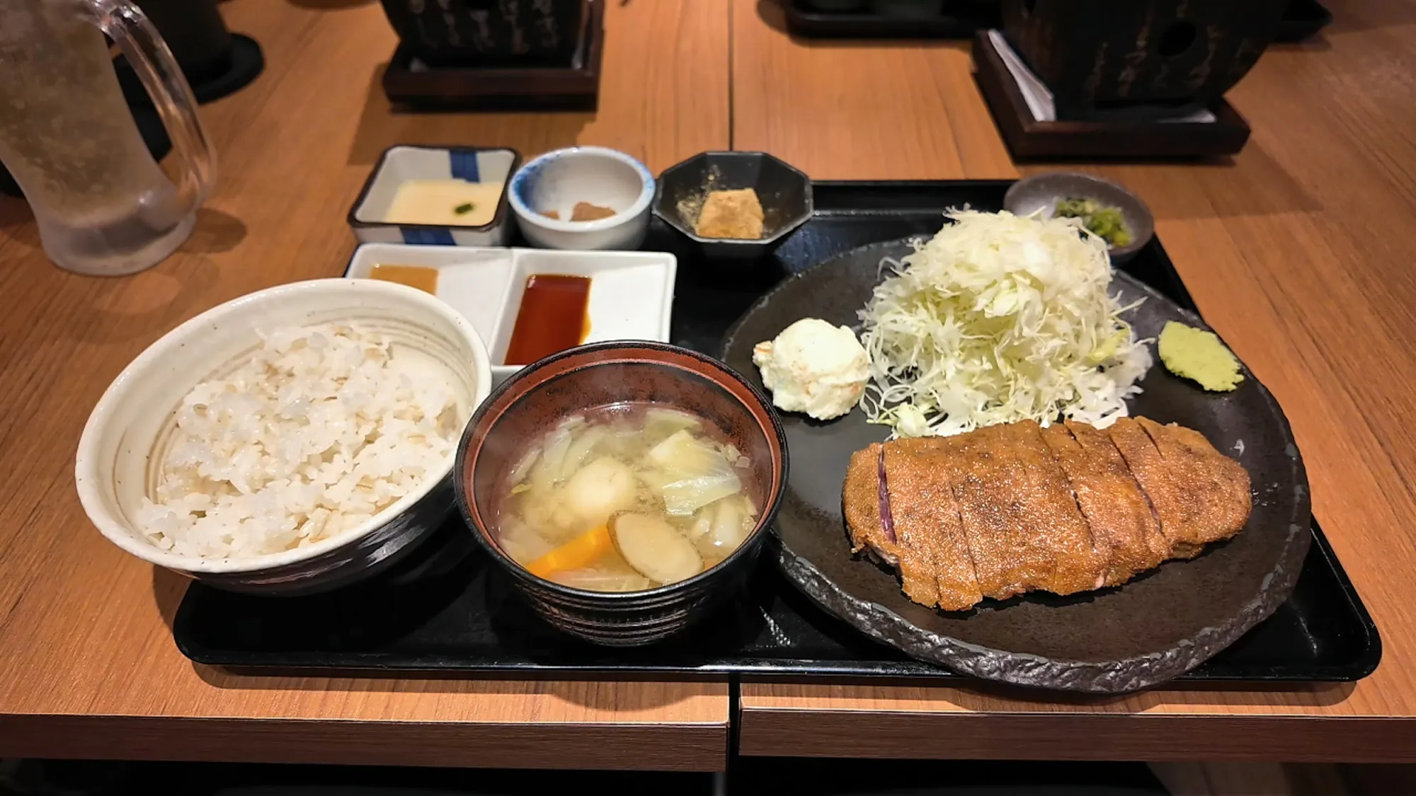 A Gyukatsu Motomura set tray with barley rice, soup, the sliced beef cutlet, shredded cabbage, and small sides