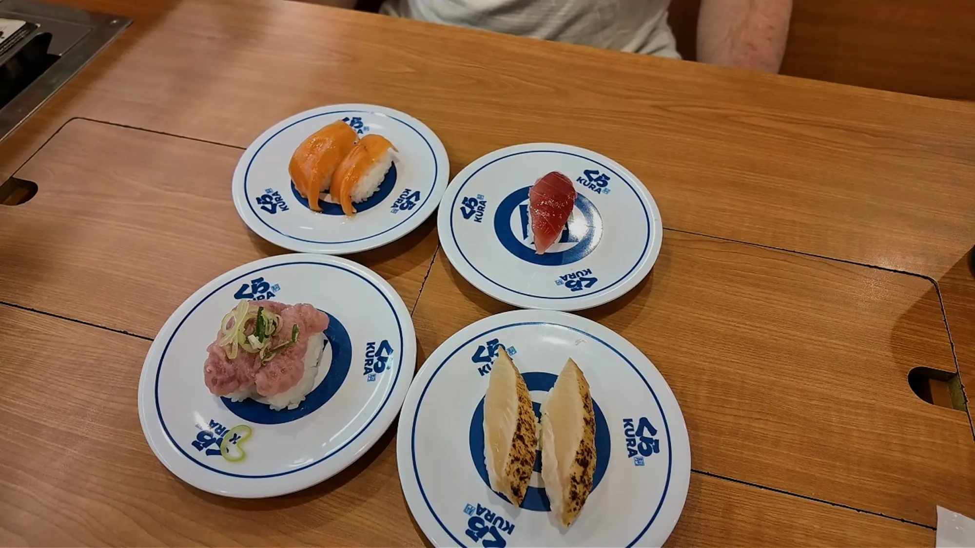 Four plates of nigiri on Kura Sushi's blue-rimmed plates