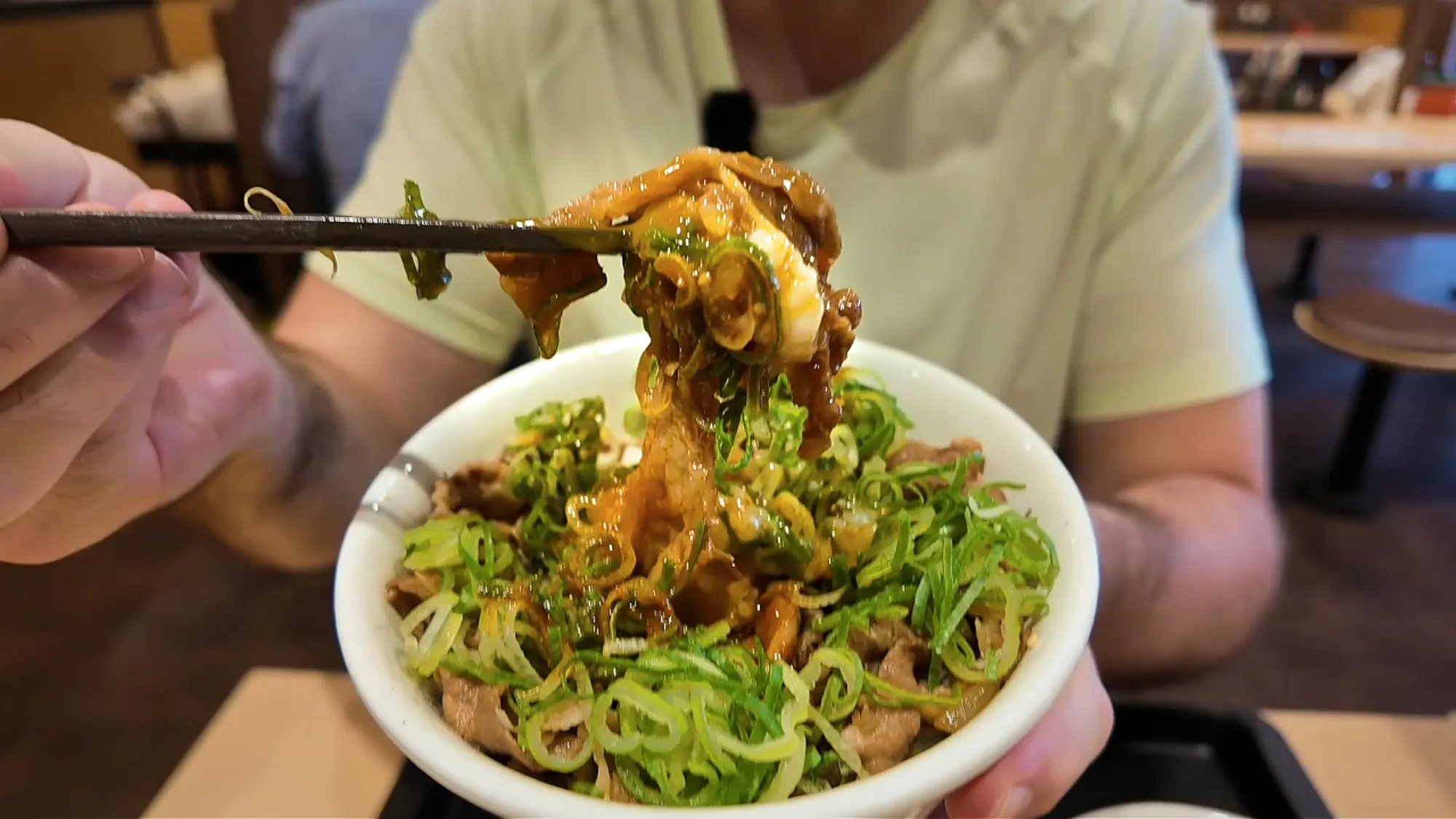 Chopsticks lifting beef, egg, and green onion out of a Matsuya gyudon bowl