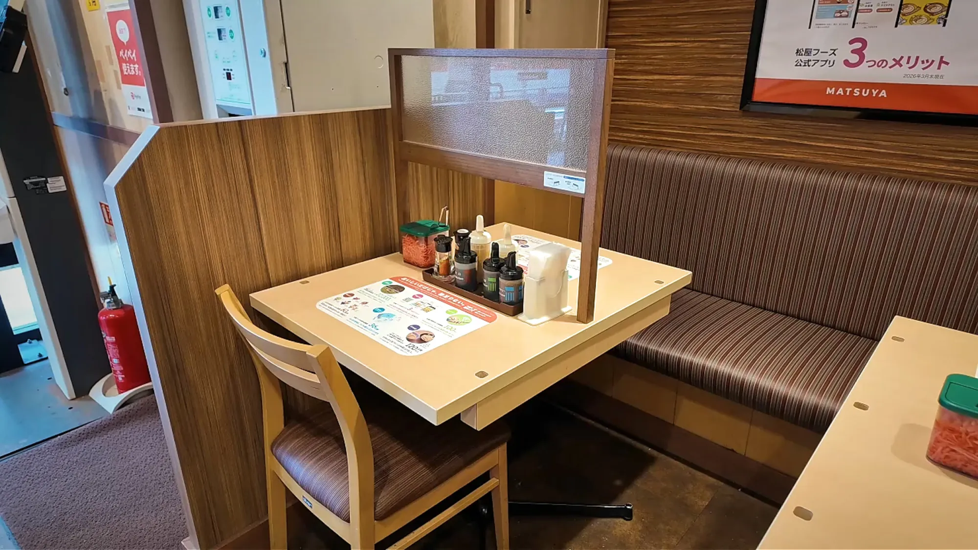 An empty two-seat booth with a low divider at a Matsuya beef bowl restaurant in Tokyo.