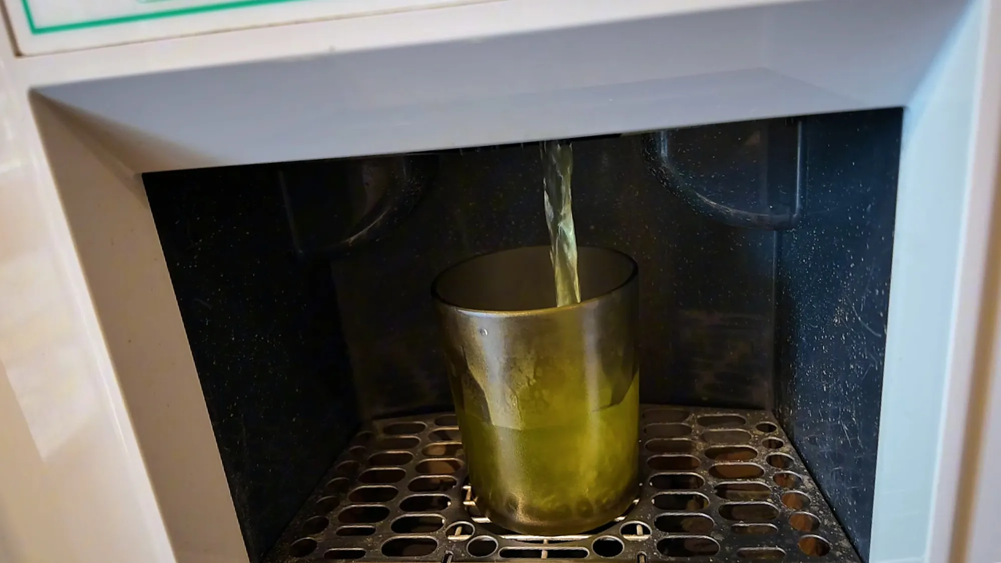 Green tea pouring from a self-serve dispenser into a glass at a Tokyo chain restaurant.