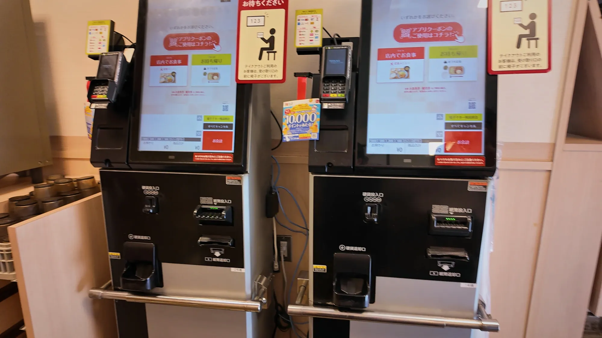 Two self-service ordering kiosks with card readers at the entrance of a Yayoiken restaurant in Tokyo.