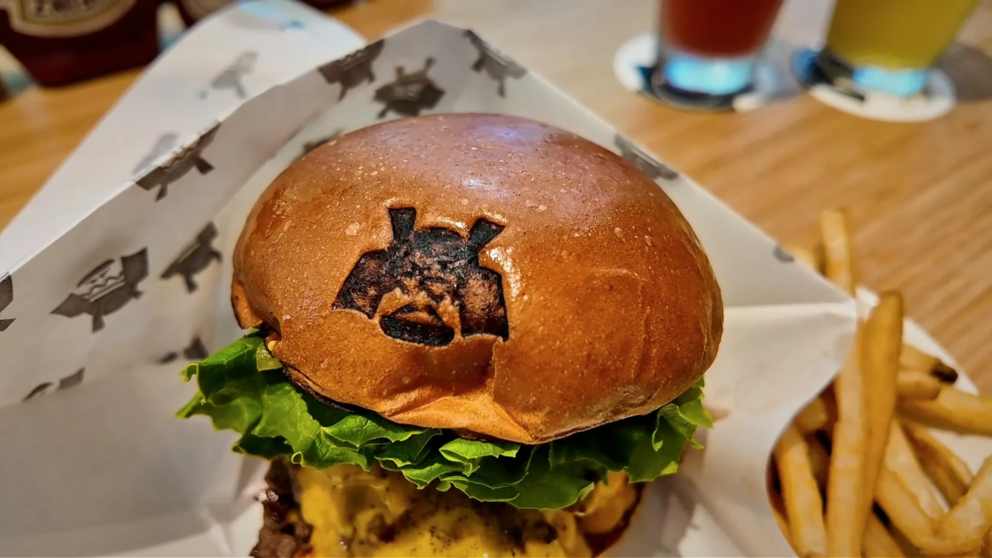 A Shogun Burger double wagyu cheeseburger with the samurai helmet logo branded on the bun, served with fries
