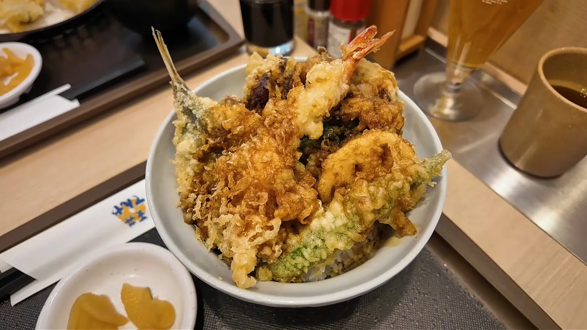 A tempura rice bowl piled with shrimp, fish, and vegetable tempura at Tendon Tenya, a Japanese chain restaurant in Tokyo.