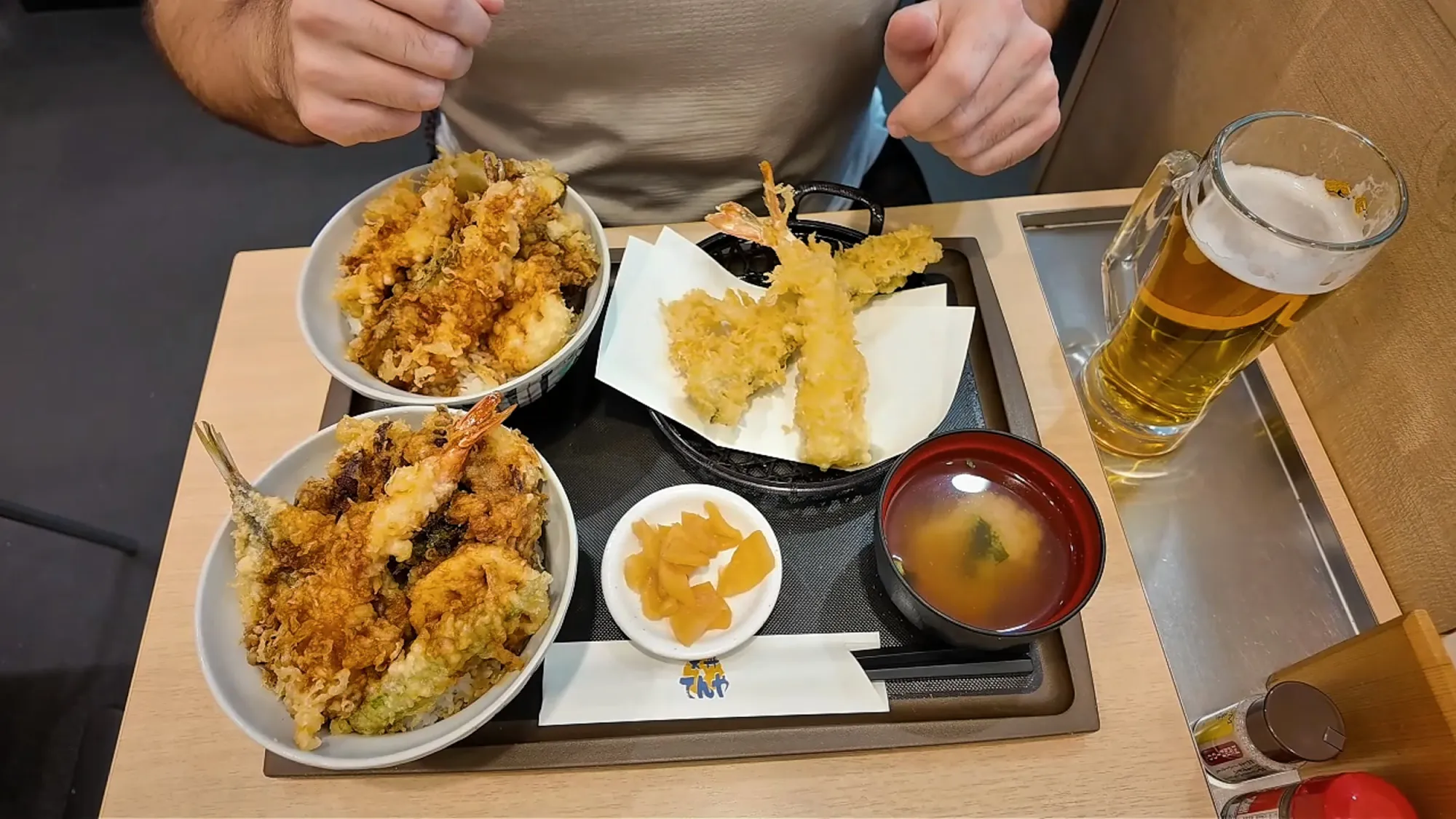 Our table at Tendon Tenya with two tempura rice bowls, a basket of large shrimp tempura, miso soup, pickles, and a mug of draft beer.