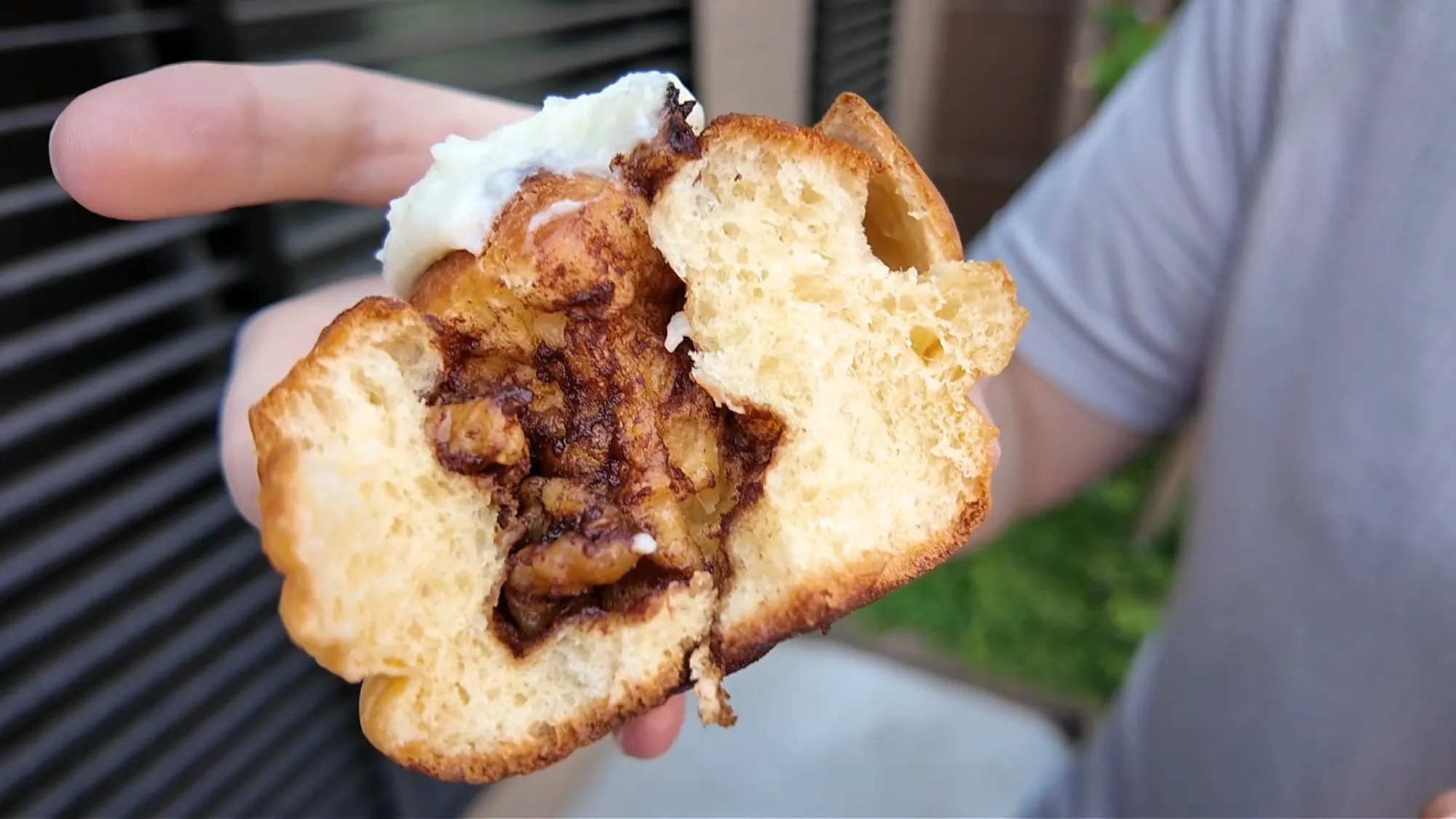 The cinnamon roll torn open to show its soft, bouncy dough and the spiced cinnamon filling under the icing