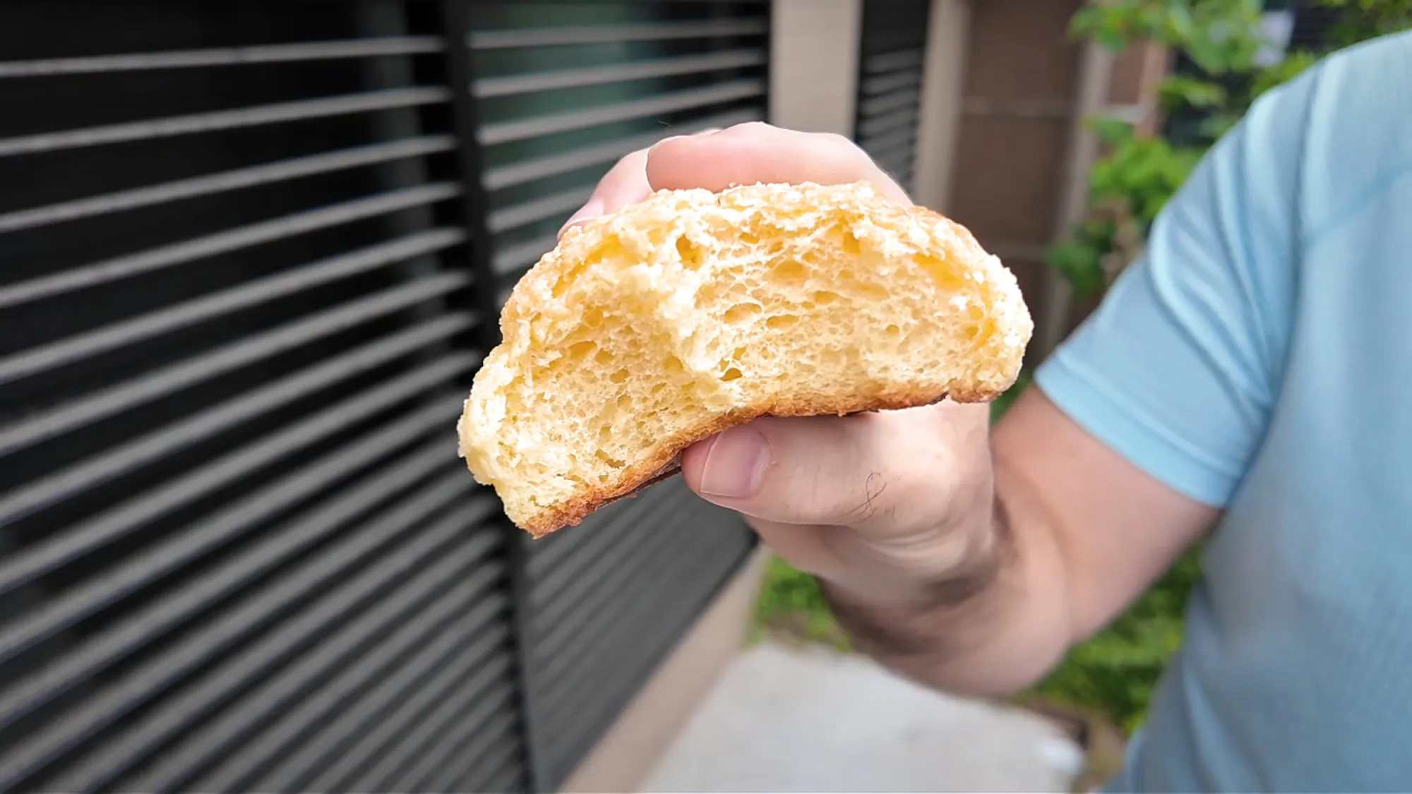 A melon pan torn in half to show its light, airy crumb under the crackly golden sugar crust