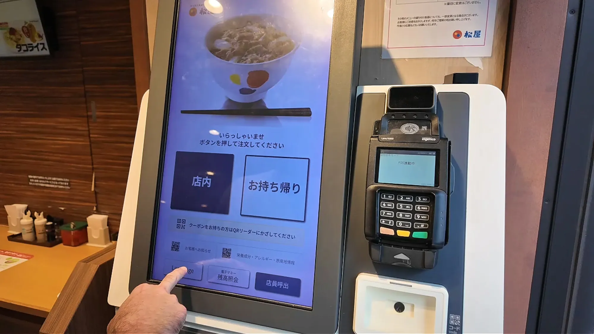 A touchscreen ordering kiosk at Matsuya in Tokyo with a card payment terminal mounted beside it.
