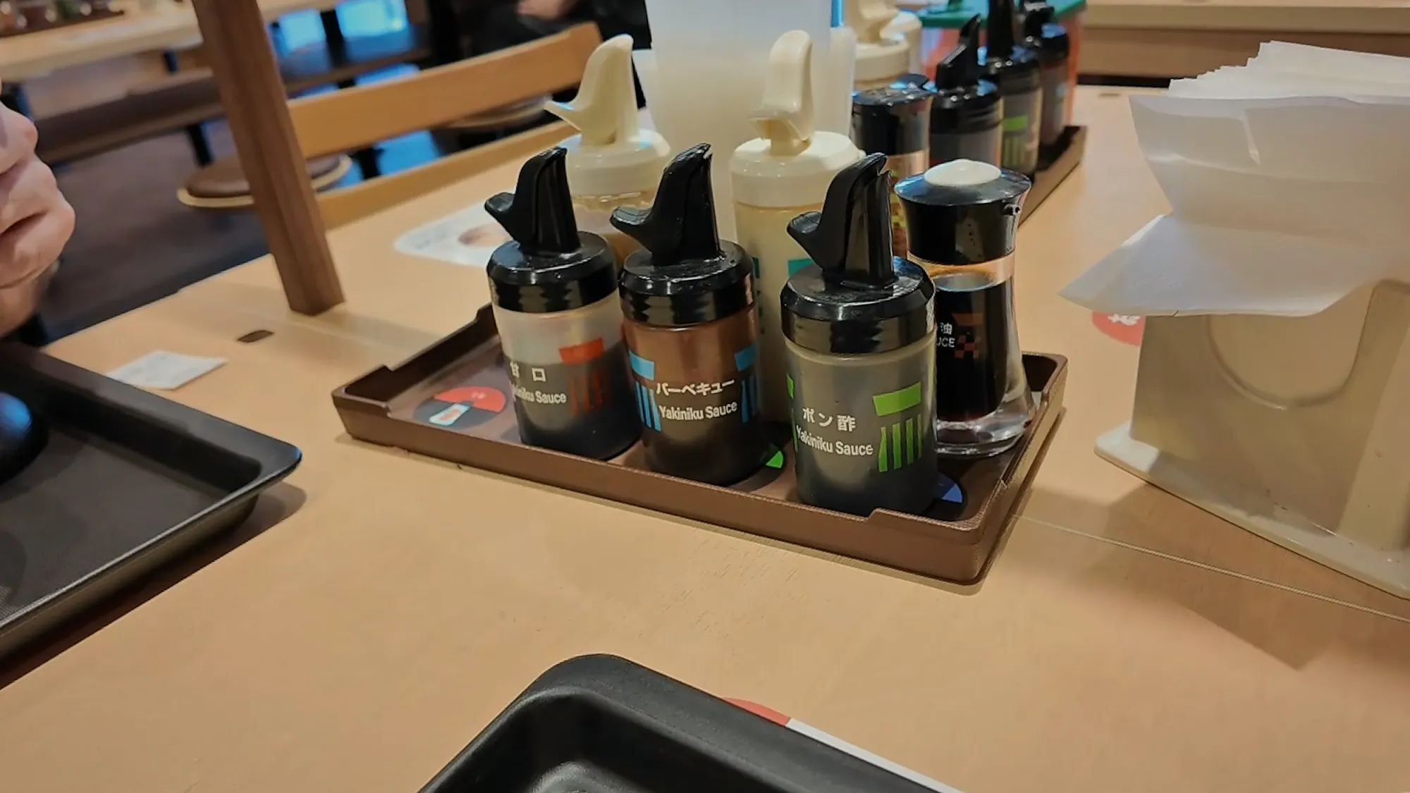Bottles of yakiniku sauce, soy sauce, and seven spice lined up on a table at Matsuya in Tokyo.