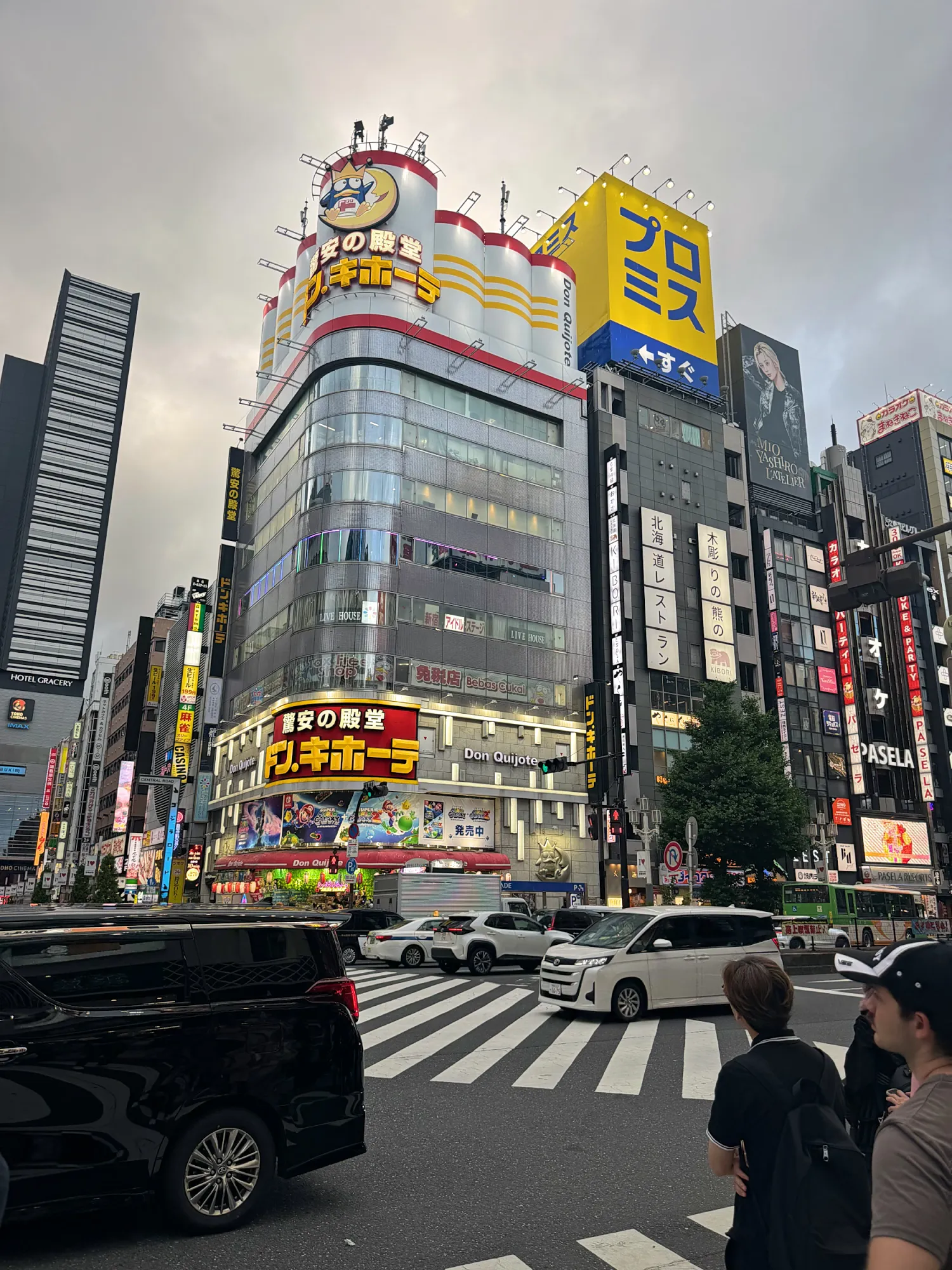 The Don Quijote discount store building in Shinjuku, Tokyo, covered in bright yellow and red signs above a busy crosswalk.
