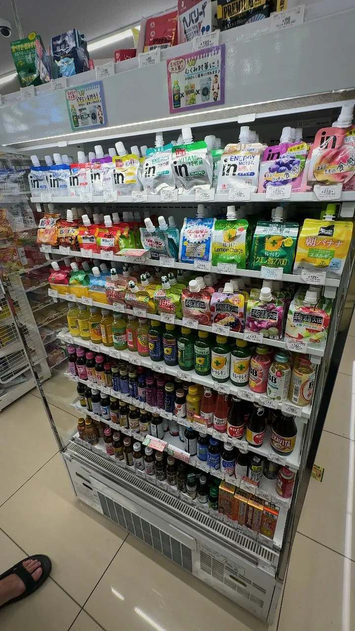 A tall 7-Eleven fridge in Tokyo with jelly drink pouches on the top shelves and small vitamin and energy drink bottles below.