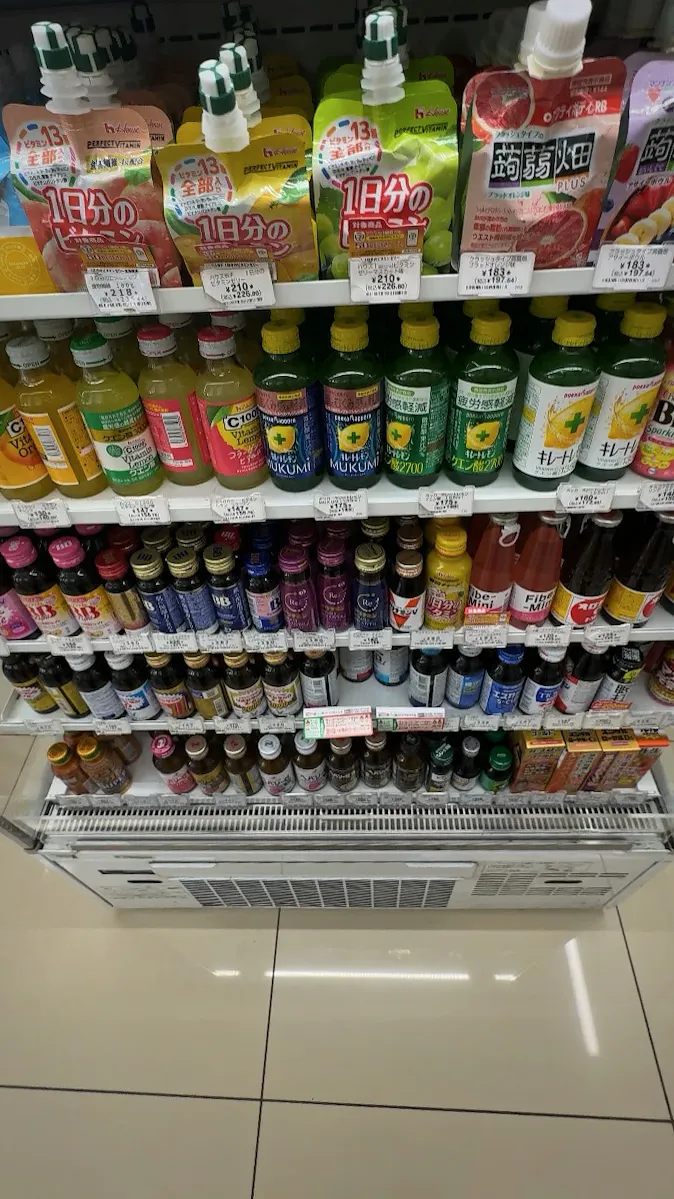The vitamin and energy drink shelves in a Tokyo 7-Eleven, with jelly drink pouches on top and rows of small glass bottles below.
