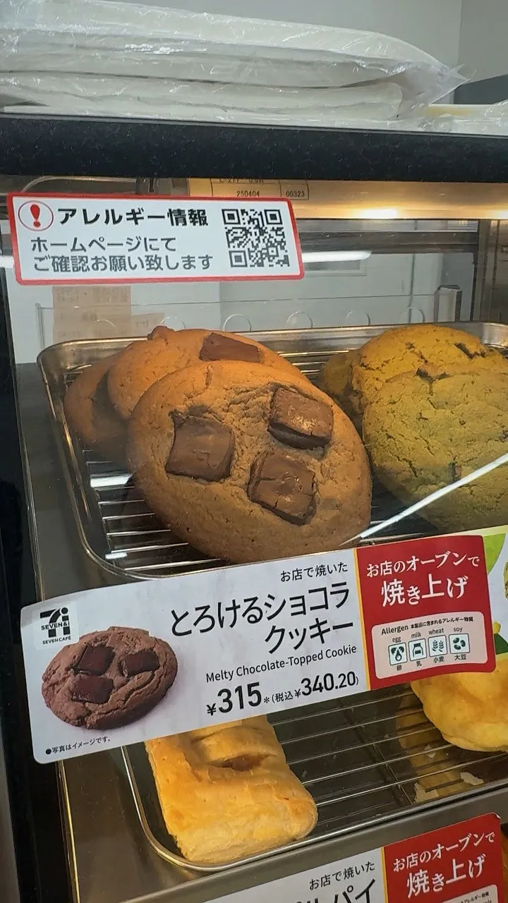 A tray of 7-Eleven Melty Chocolate Cookies with big chocolate chunks behind a sign saying baked in store, 315 yen before tax.