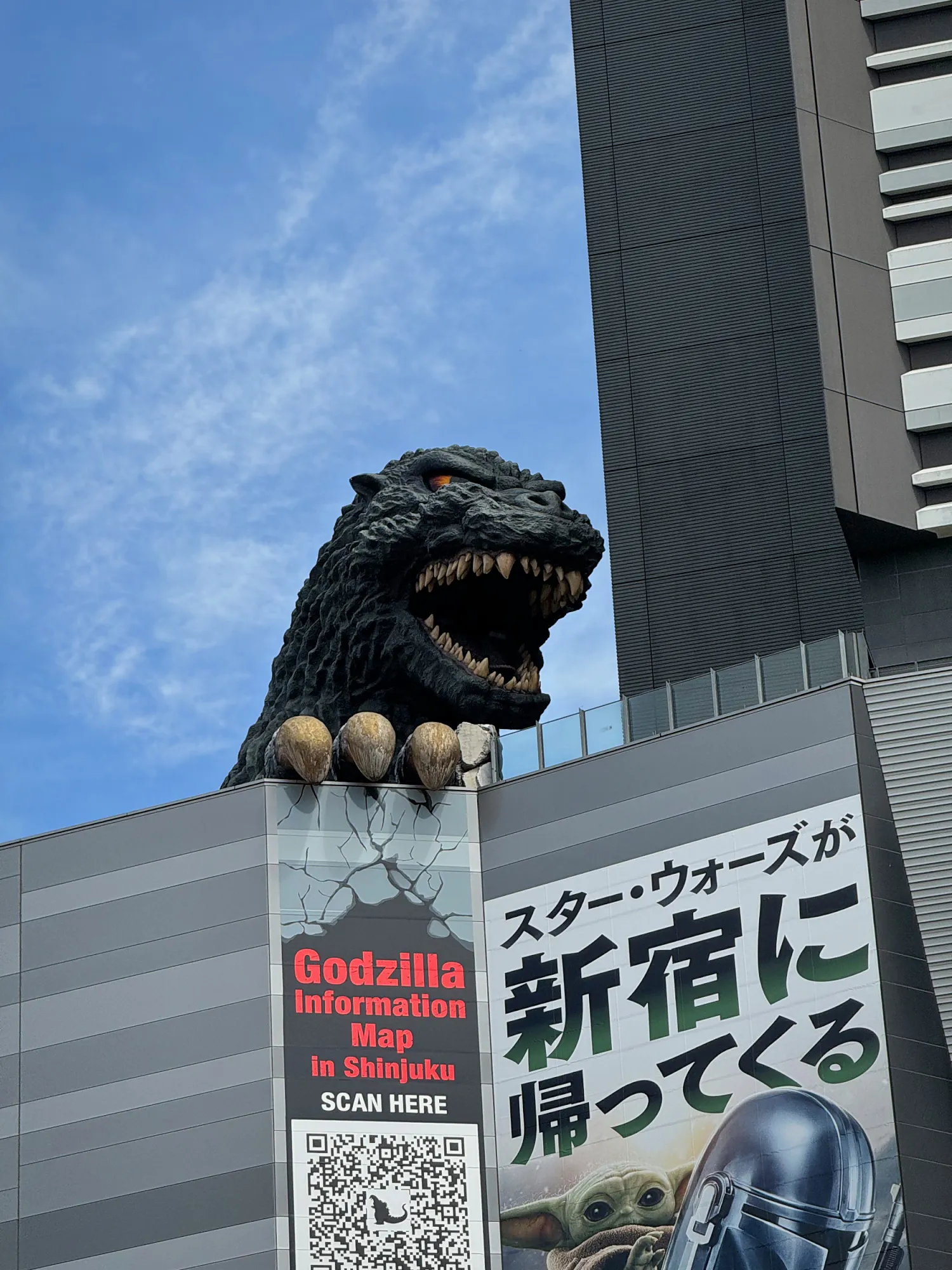 The Godzilla head on top of the Shinjuku Toho Building in Kabukicho, Tokyo, against a blue sky.
